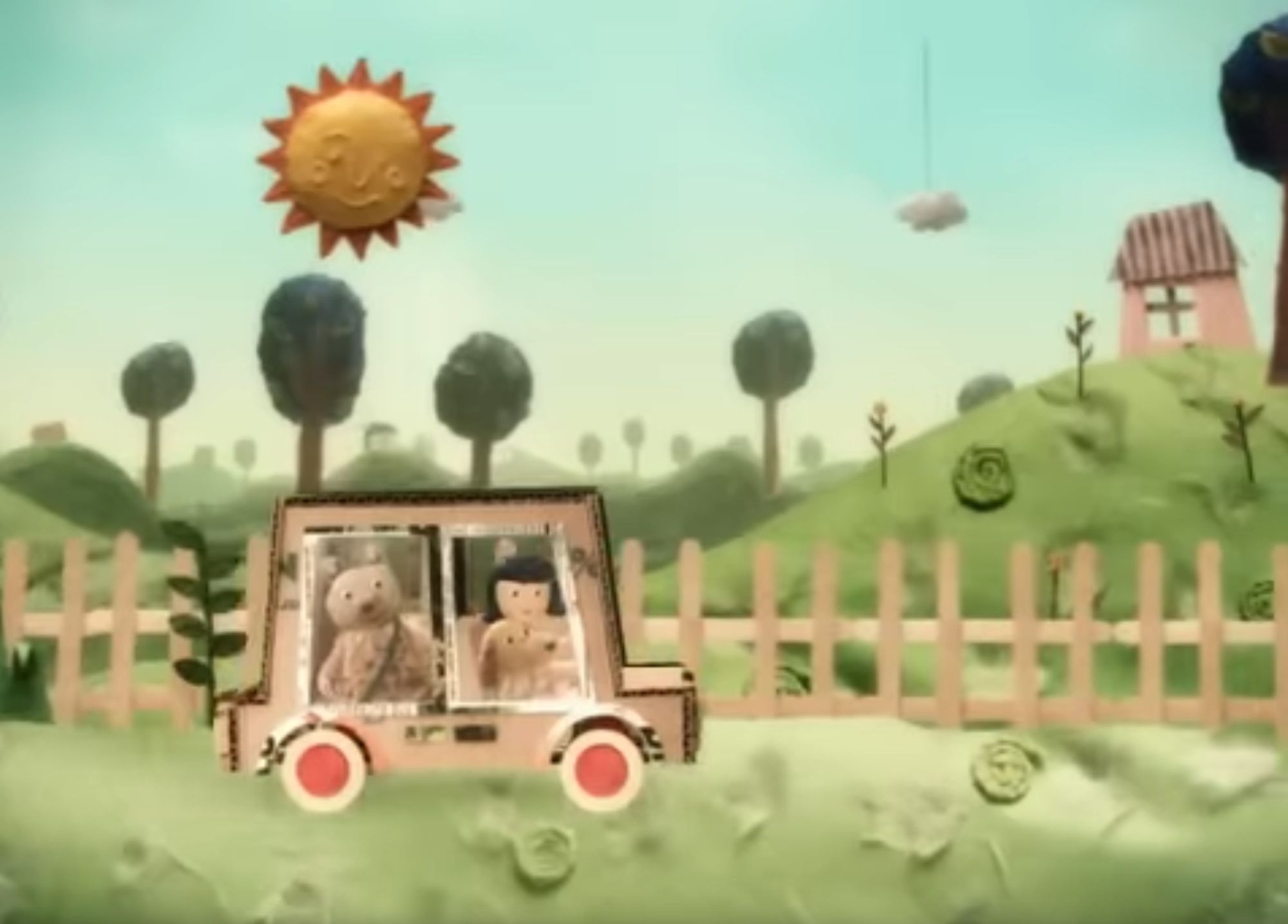 The titular electric car, now carrying the woman, dog, and bear, drives through a verdant paper field past a popsicle-stick fence under a smiling clay sun.