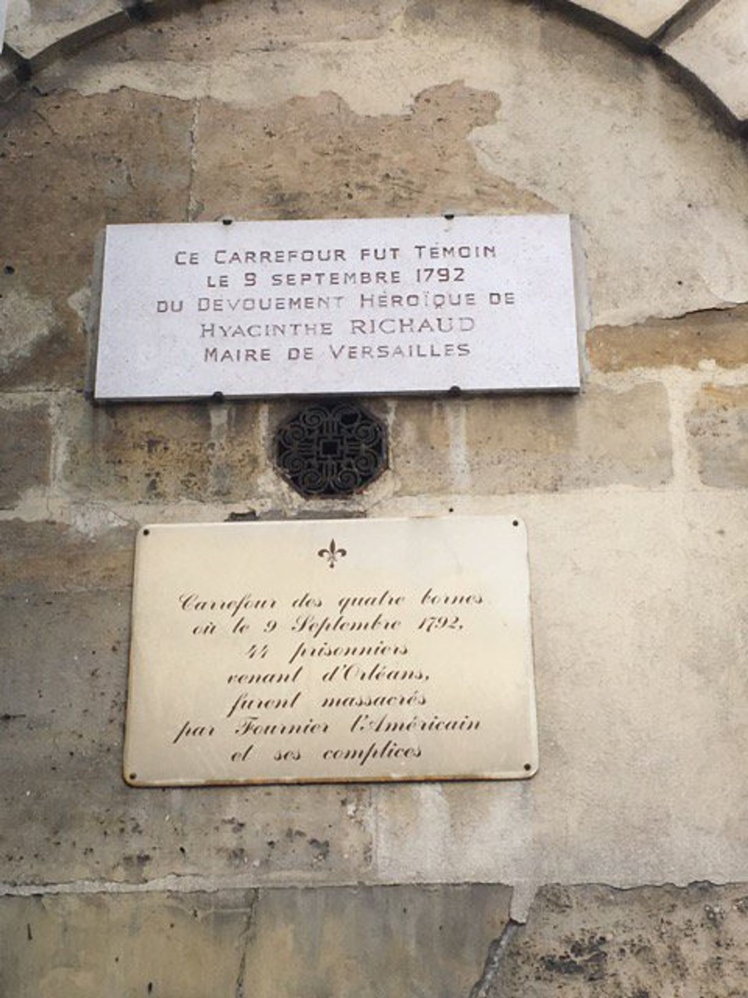 2 plaques on the stone wall of a building beneath an arch in relief

CE CARREFOUR FUT TÉMOIN
KE 9 SEPTEMBER 1792
DU DEVOUEMENT HÉROÏQUE DE
HYACINTHE RICHAUD
MAIRE DE VERSAILLES

brass (?) plaque, fleur-de-lys at top, text in script:

Carrefour des quatre bornes
où le 9 September 1792,
44 prisonniers
venant d'Orléans,
furent massacrés
par Fournier l'Américan
et ses complices