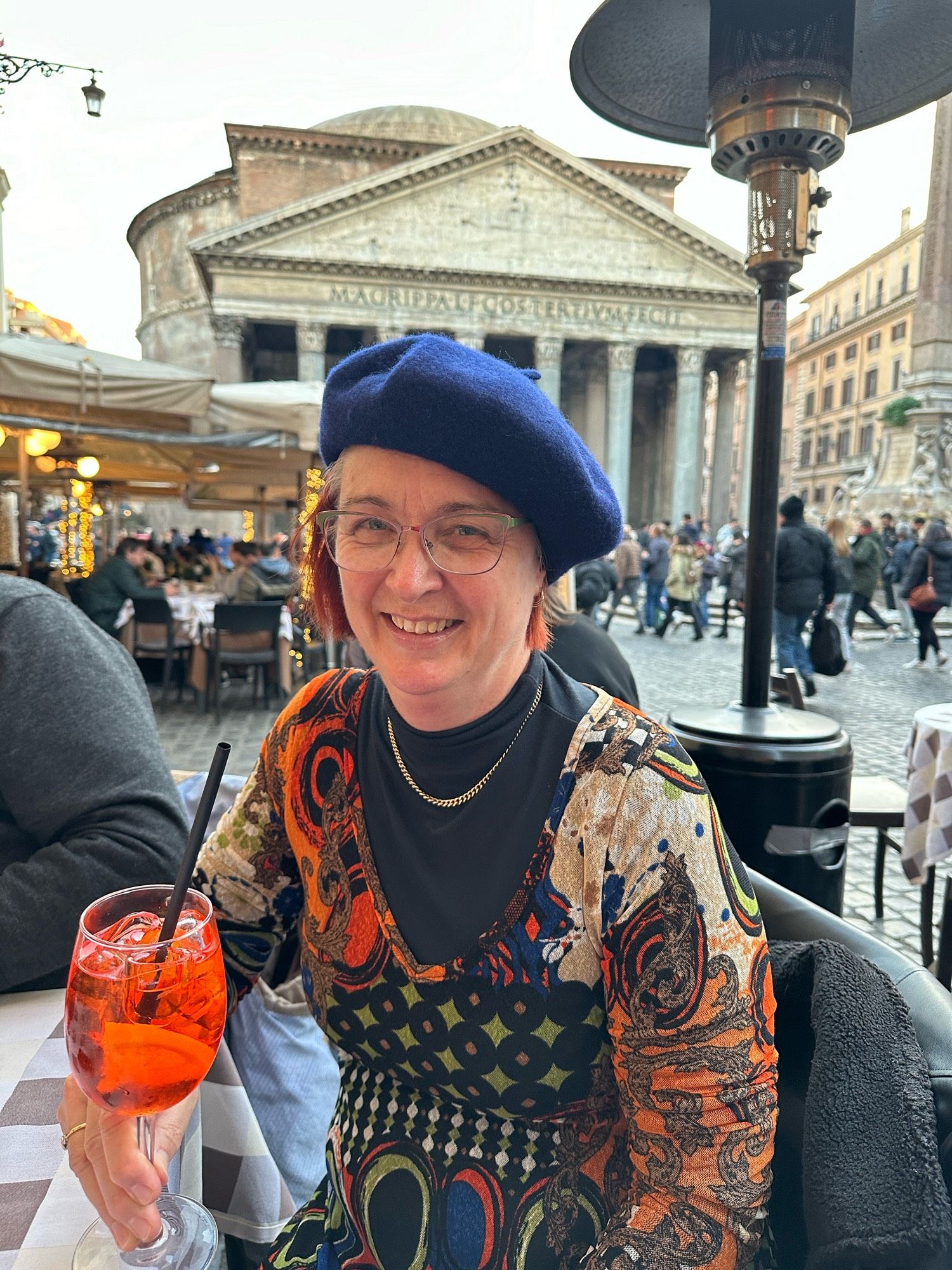 Me, wearing a blue beret, with an aperol spritz in hand, at a cafe outside the Pantheon.