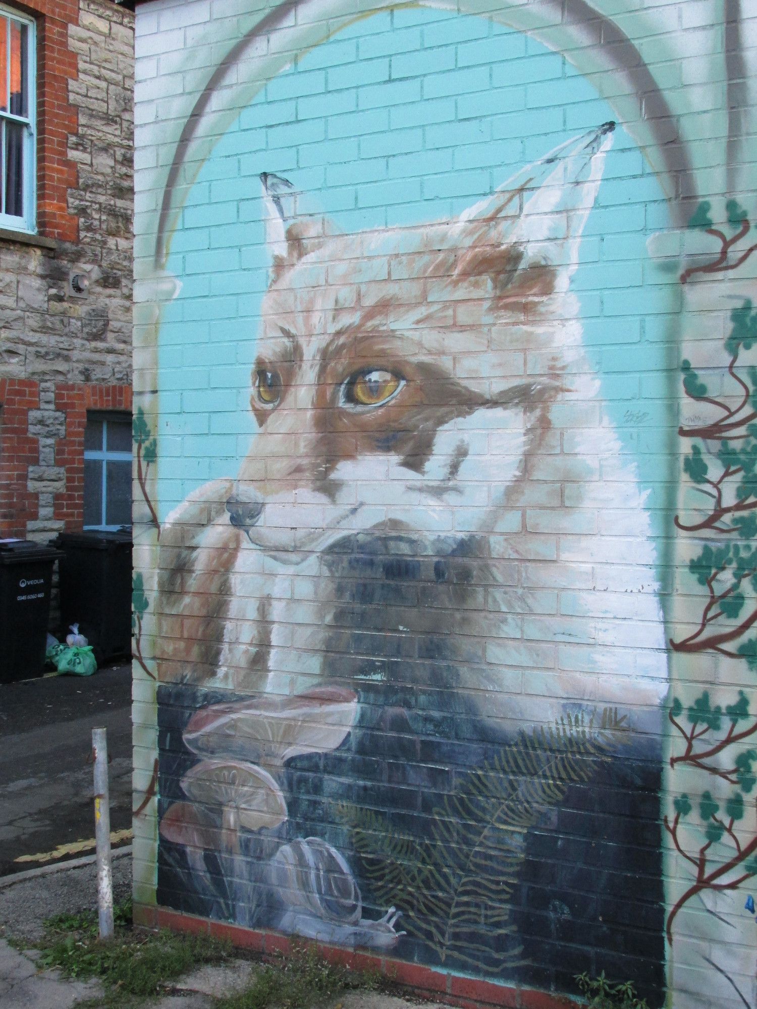 Street art of a fox in an archway, in profile against a light blue background. Spotted in Glastonbury, UK.