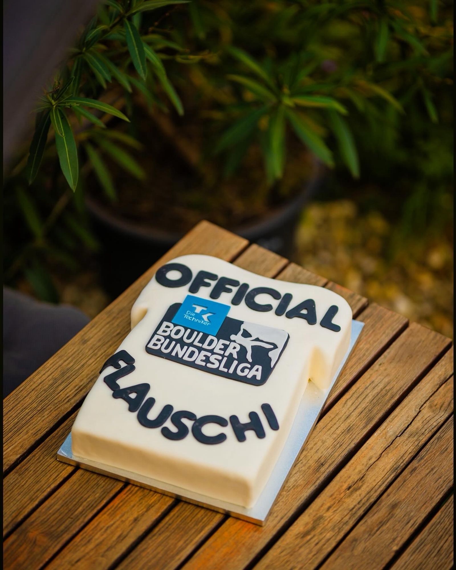 Torte in Form eines weißen T-Shirts mit Logo der Boulder Bundesliga und der Aufschrift „Official Flauschi“