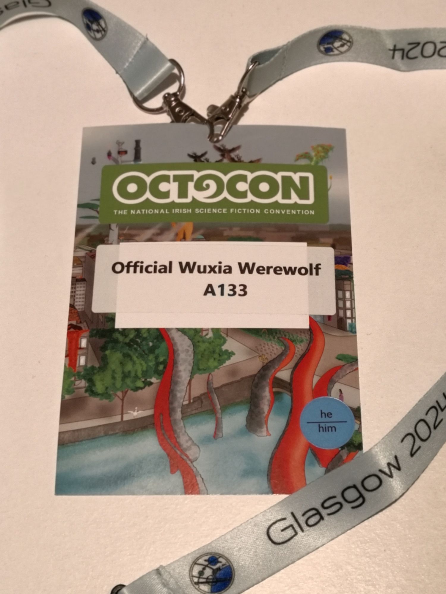 A lanyard for Octocon 2024 with "Official Wuxia Werewolf" written on the badge. The art for the event is featured in the background.