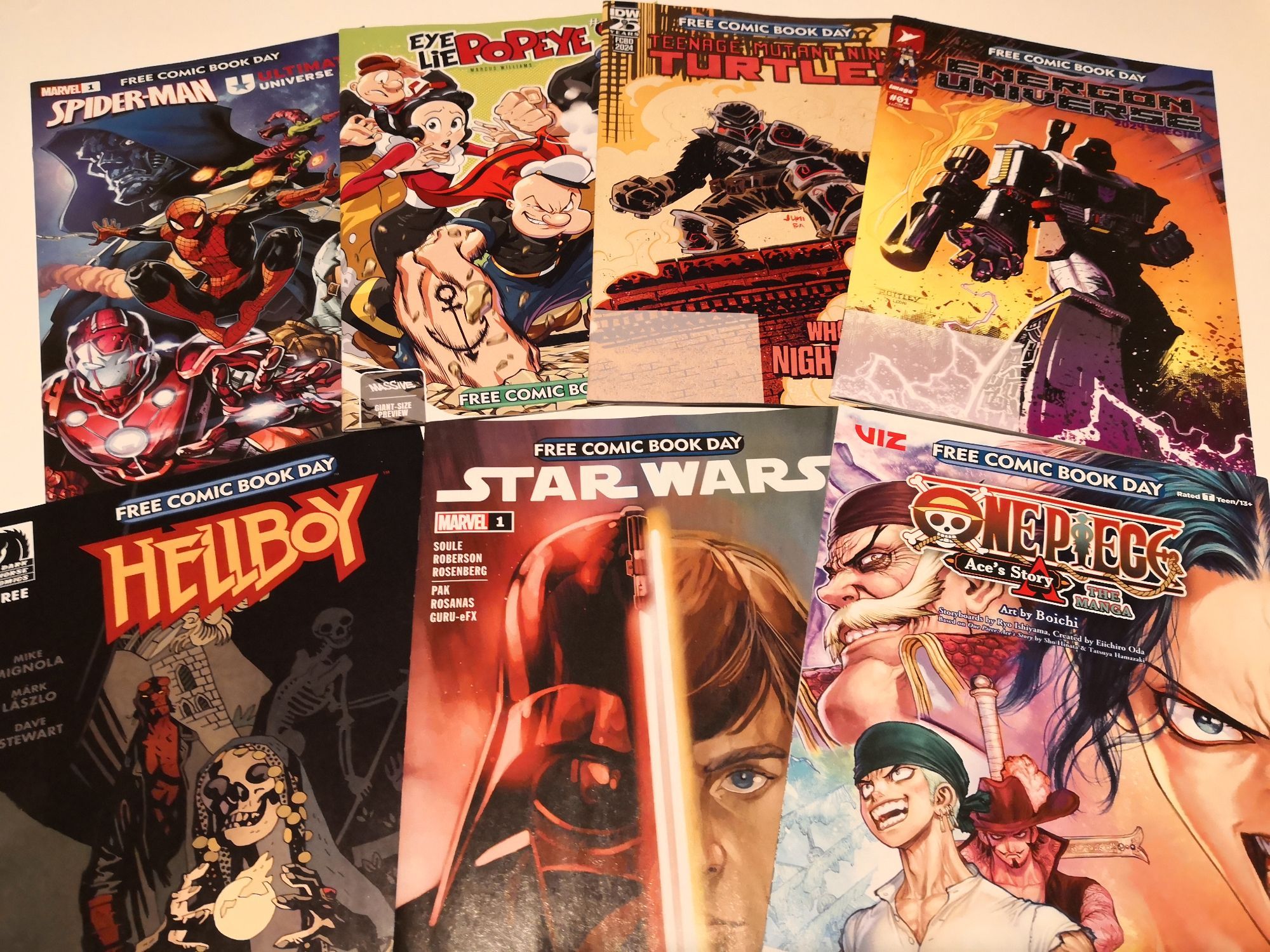 A collection of comics including Transformers, Teenage Mutant Ninja Turtles, Spiderman, PopEye, Hellboy, Star Wars, and One Piece.