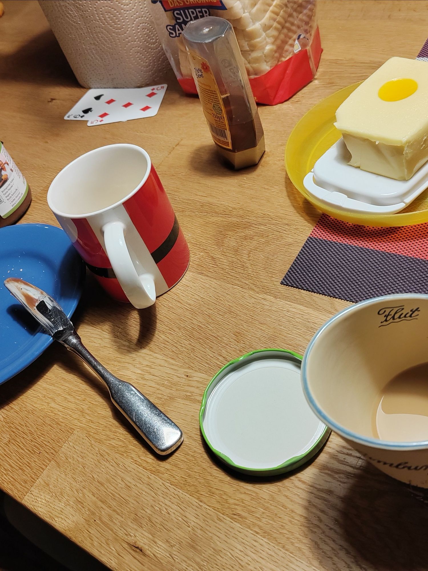 Ein Frühstücks Tisch mit Teller, Tassen, Butter, Honig und eine Tasse Kaffee.