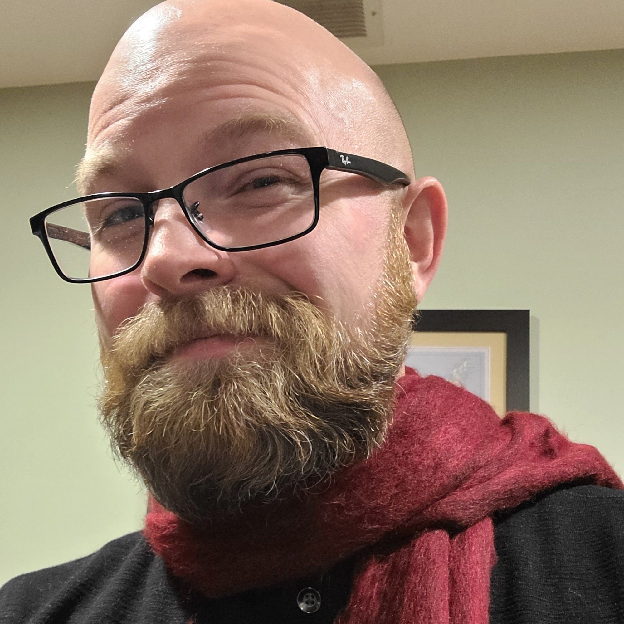 Bearded person with glasses and red scarf