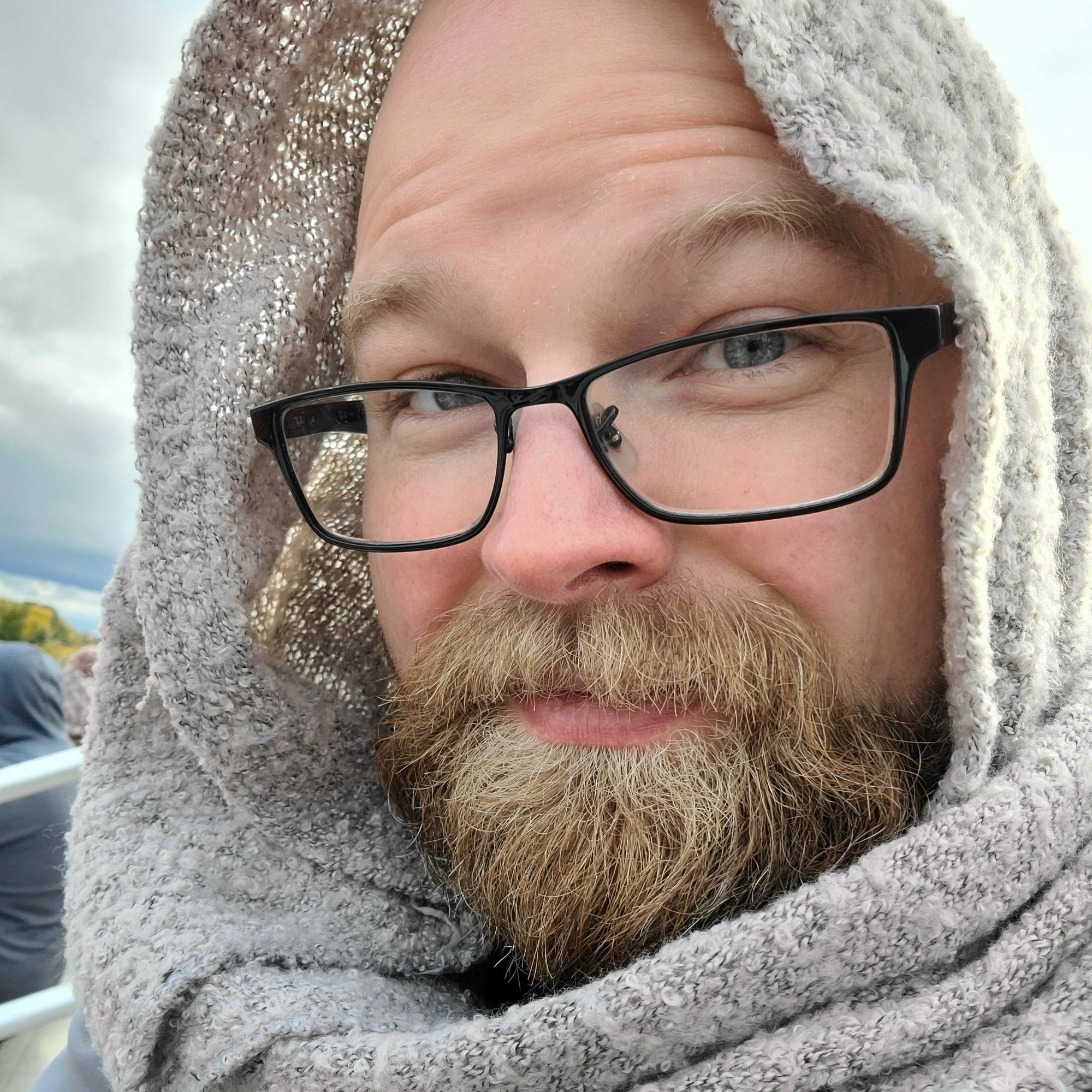 Bearded person with glasses and gray shawl