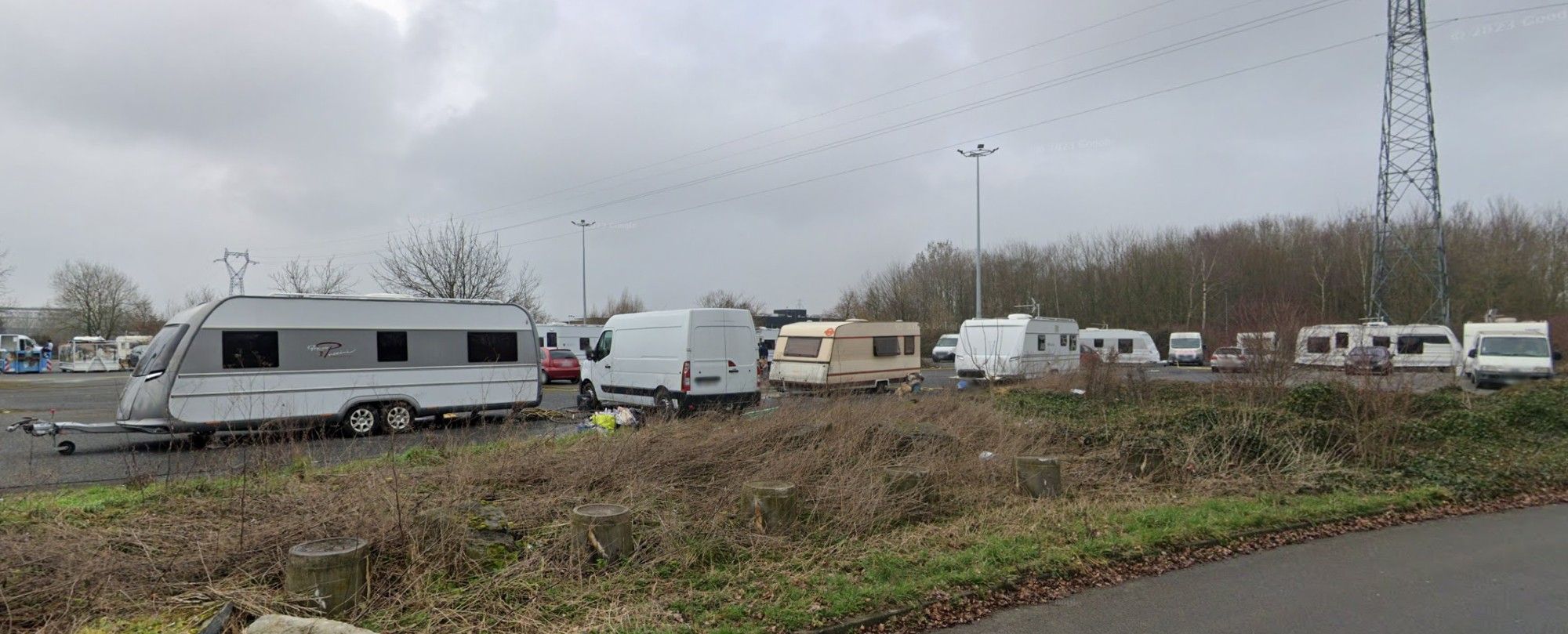 Google Street View image of a parking lot on the outskirts of Lille near the old Château d'Isenghien, full of RVs and vans, on a gray perhaps winter day.