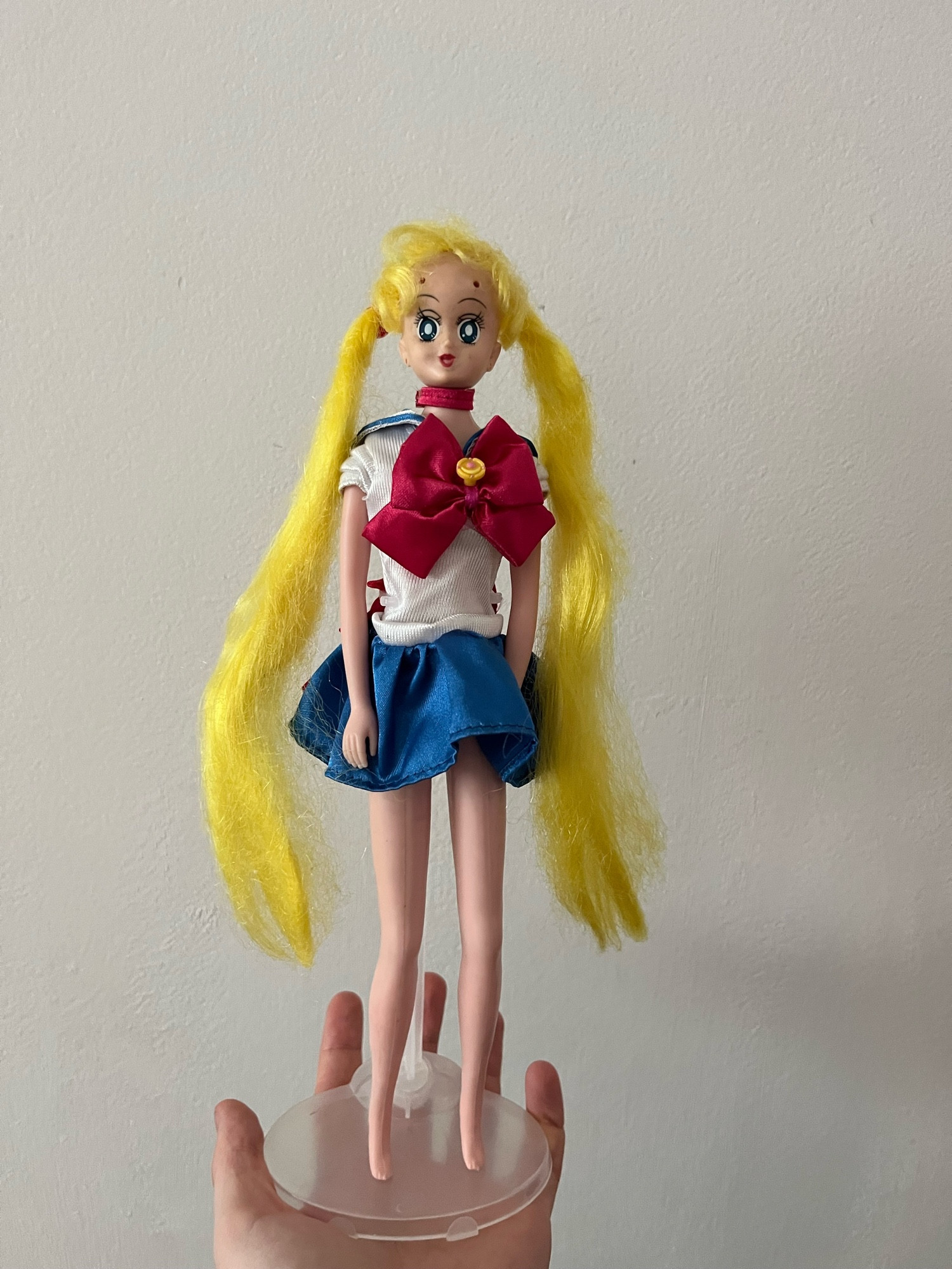 Boneca Sailor Moon com longos cabelos loiros presos dos lados, uniforme de marinheira e sem sapatos