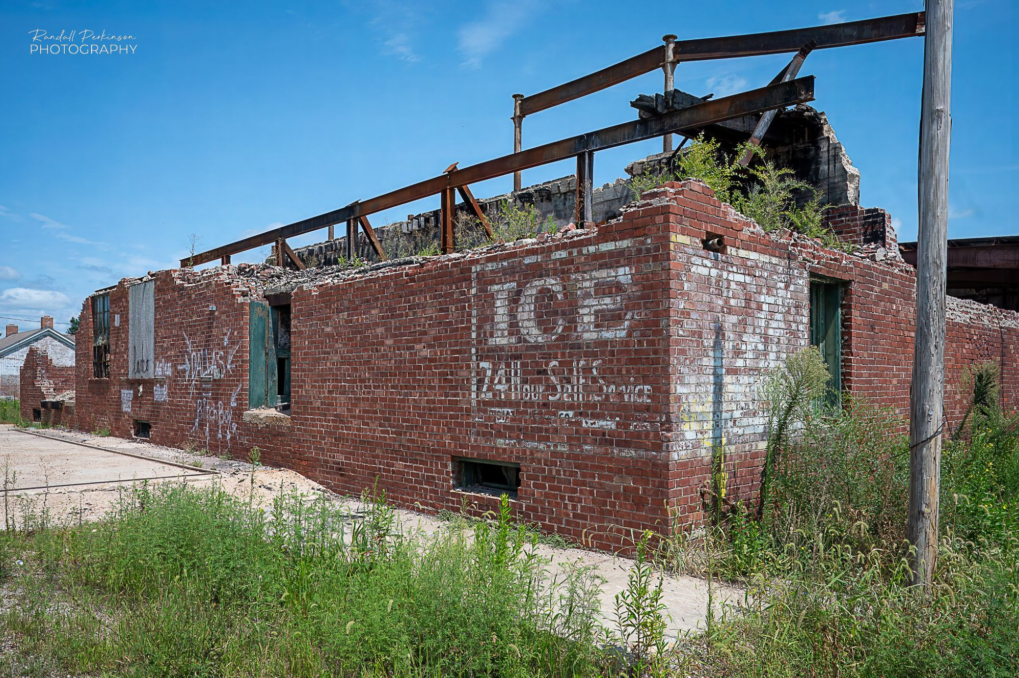 A crumbling old brick building that used to be an icehouse based on a ghost sign on the building that reads, "Ice - 24 Hour Self Service".