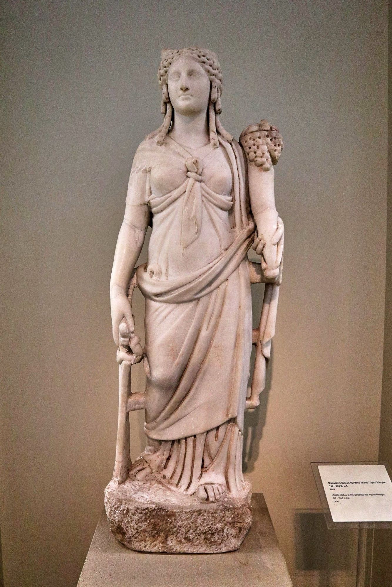 A Roman-period marble statue of Isis from Athens. She holds a cornucopia and wears a robe with a notable knot. 

Photo by George E. Koronaios (CC BY-SA 4.0)