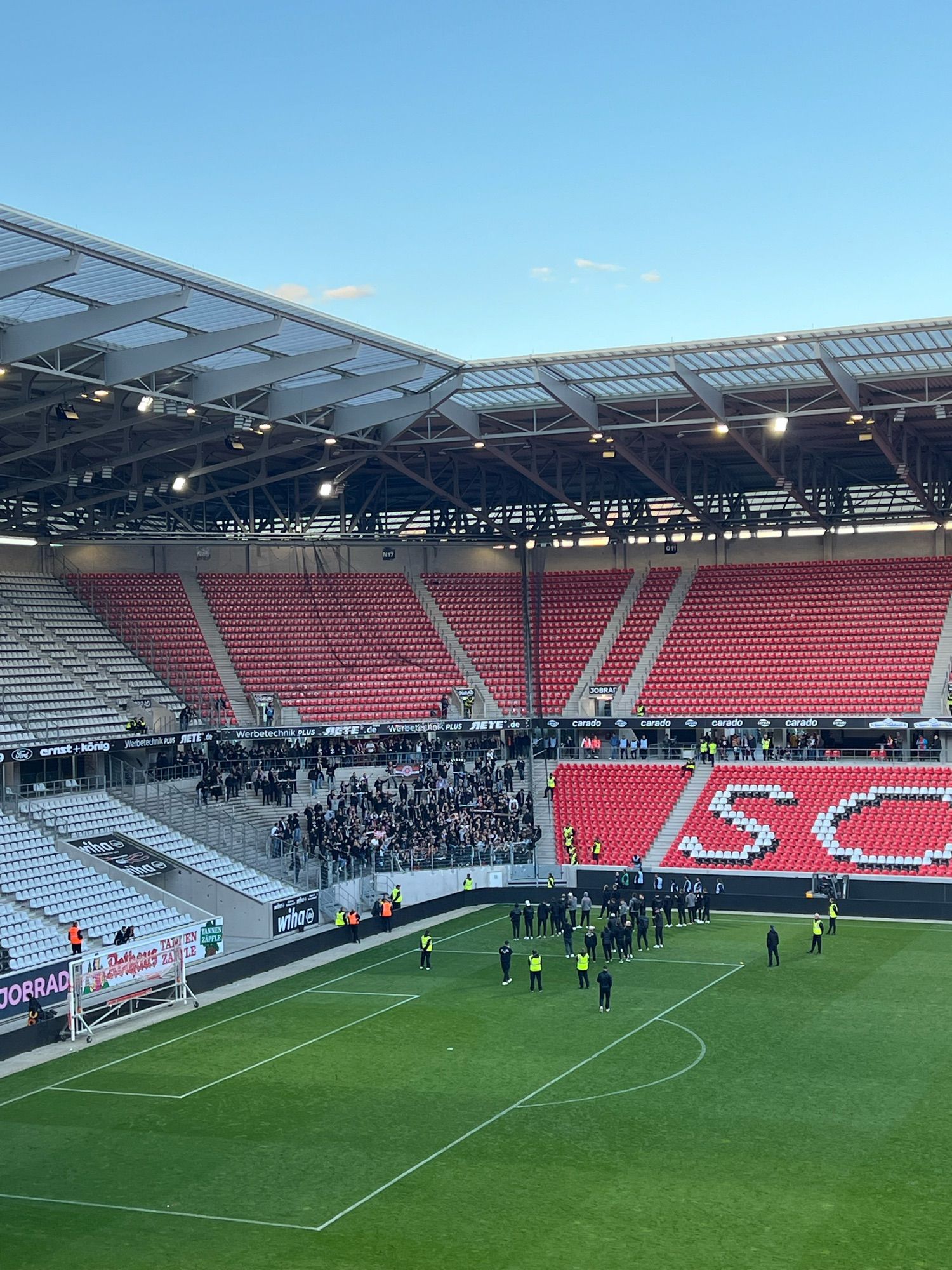 Gästeblock beim SC Freiburg mit feiernden FCSP Fans und dem FCSP Team davor auf dem rasen.