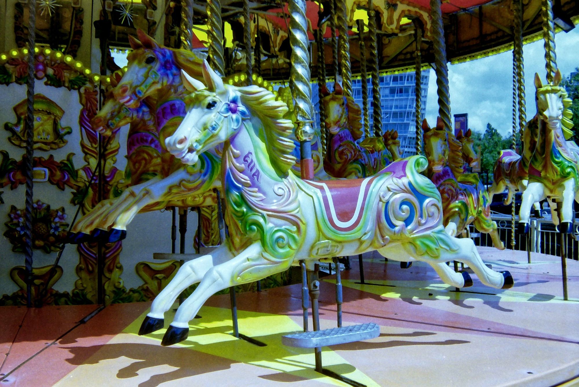 A colour photograph of 'Ella" a Merry-Go-Round horse, resplendent in all her hand-painted finery and shining brightly in the summer sunshine.