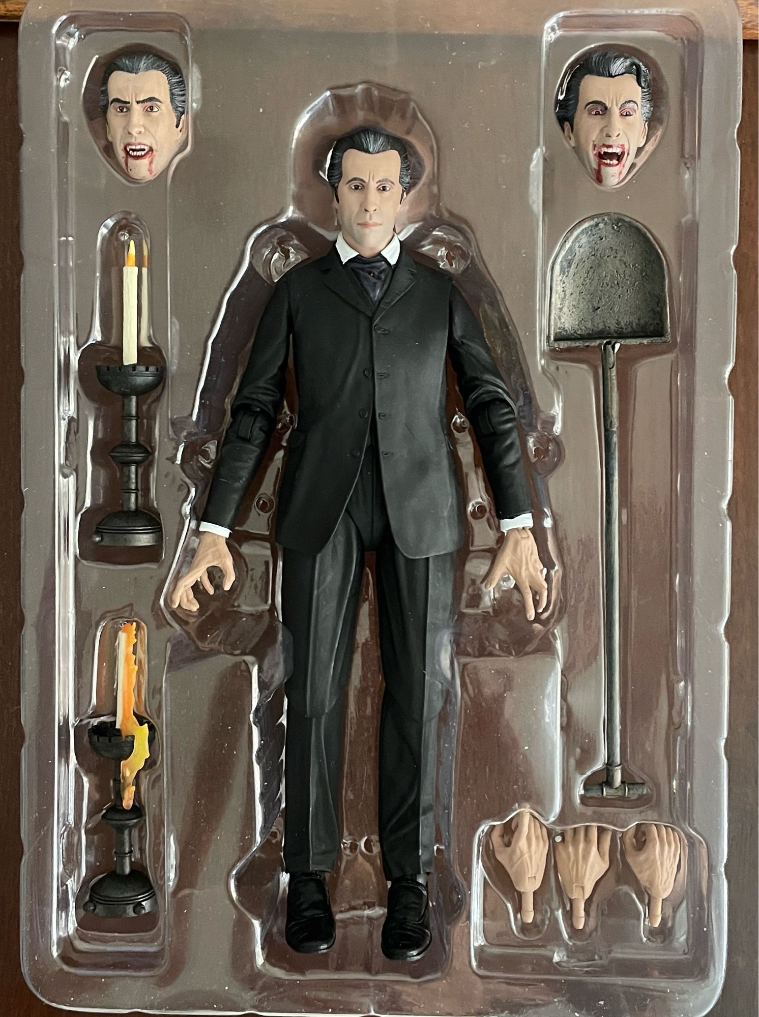 The Dracula action figure with interchangeable heads and hands and two candlesticks and a shovel. The action figure resembles  Christopher Lee.