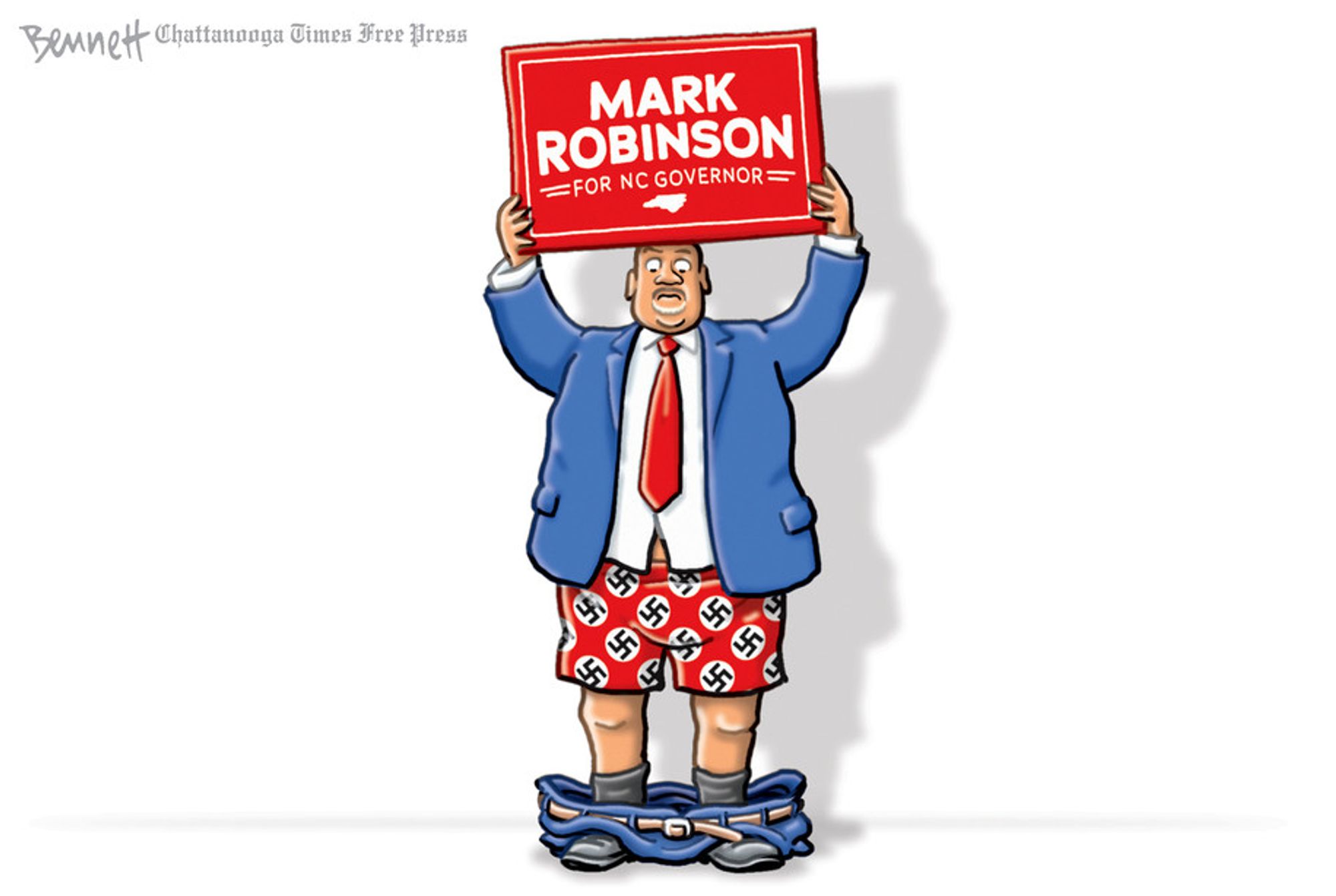 Cartoon by Clay Bennett: Mark Robinson holding campaign sign over his head with his pants down around his ankles. 