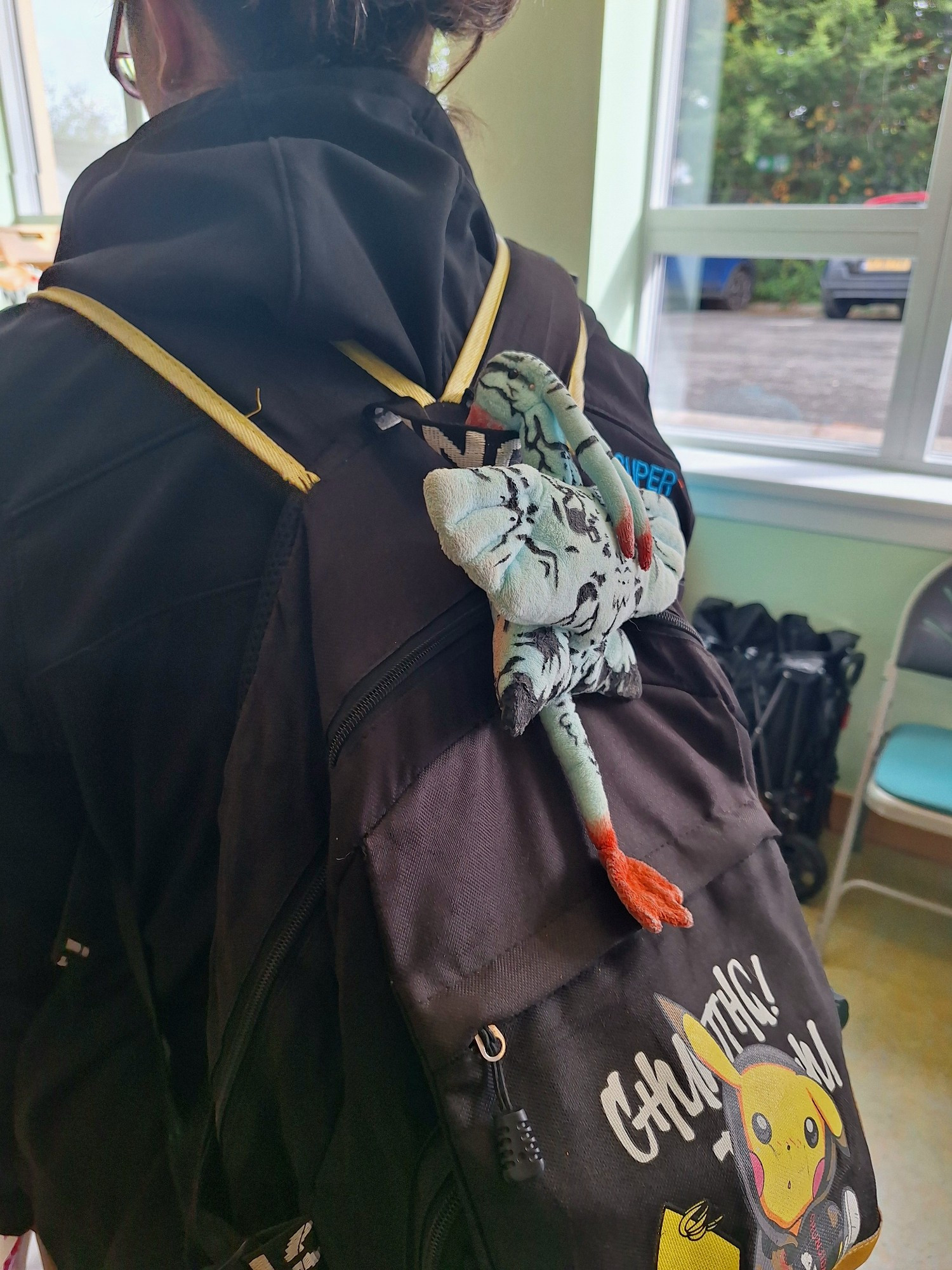 A woman standing in front of a rack of clothes. A banshee plush hangs from her bag without her knowledge.