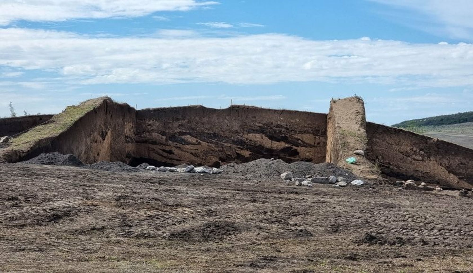 barren dirt hill with what look like two large earthen ramps rising up to it.