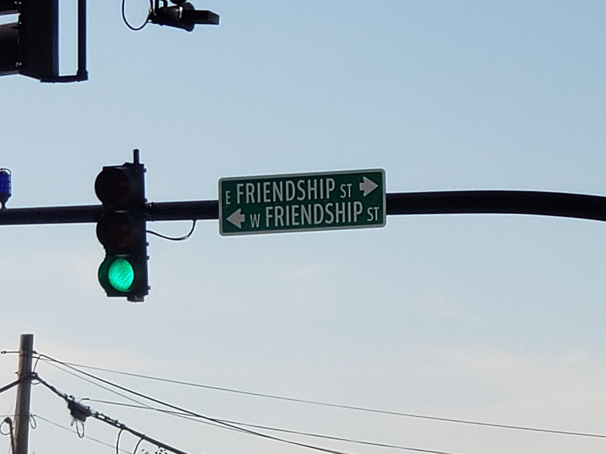 A traffic light at an intersection; the street sign attached reads "E Friendship St" with an arrow pointing right, and "W Friendship St" with an arrow pointing left.