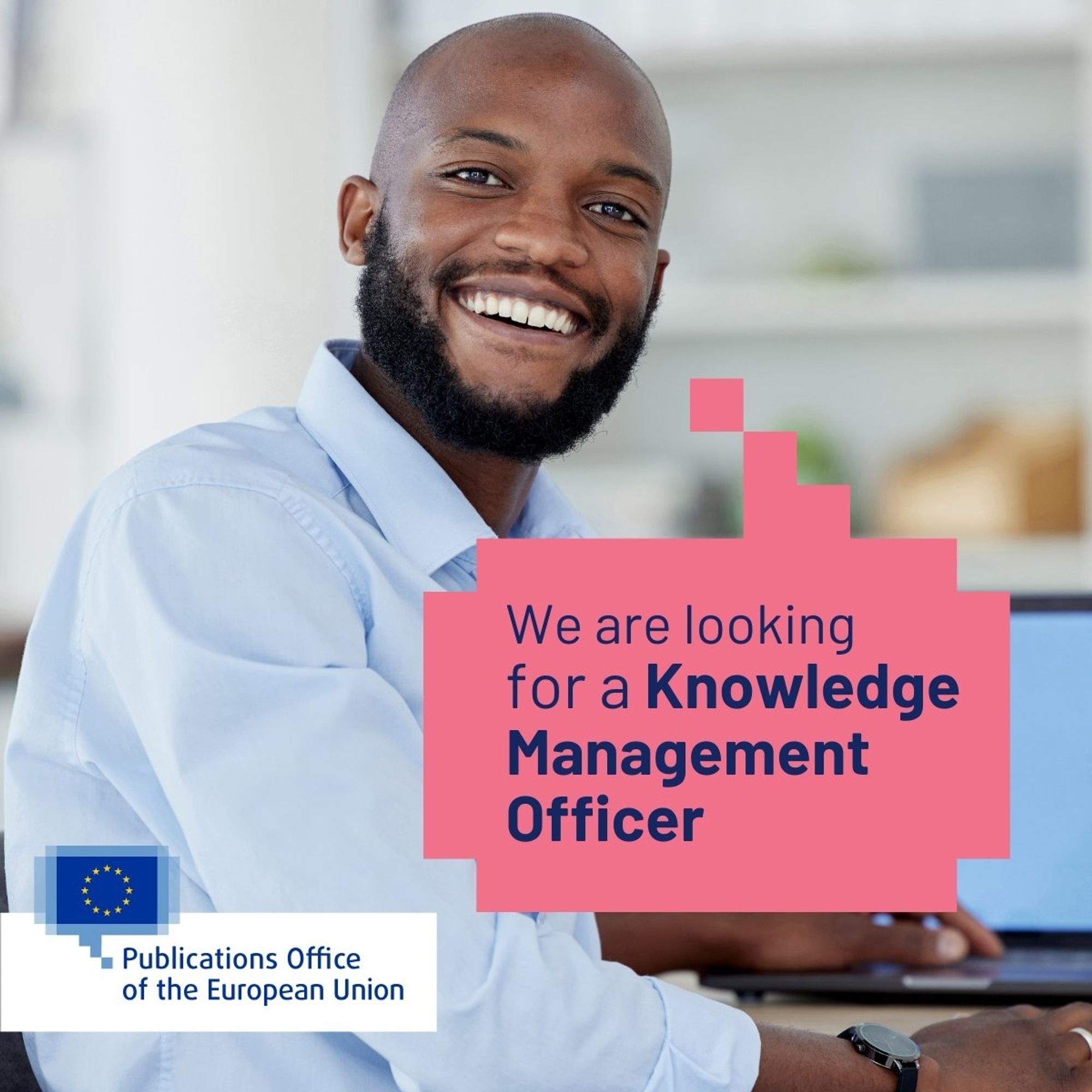 On the left and in the background there is a young man working at his desktop and smiling at us. The speech bubble says 'We are looking for a Knowledge Management Officer.'