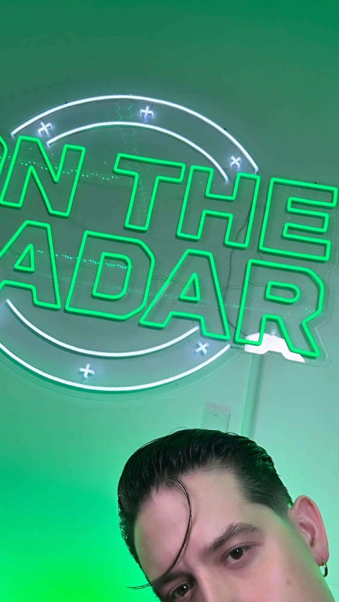 Gerald E. Gillum  in the corner of a photo framed to show off part of the ‘on the radar’ neon logo with a ombré green background