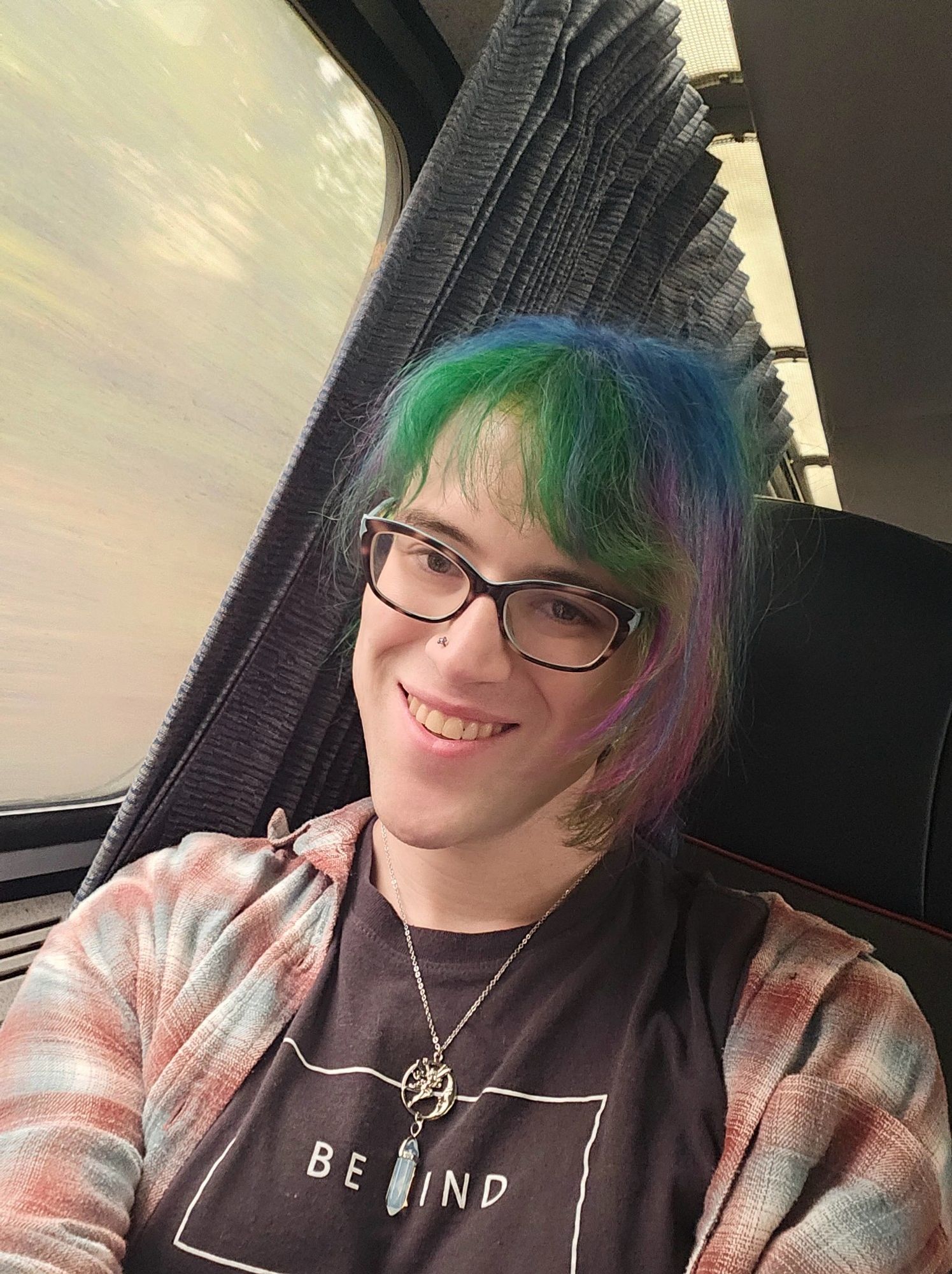 Train selfie of skye wearing a shirt that says "Be Kind"