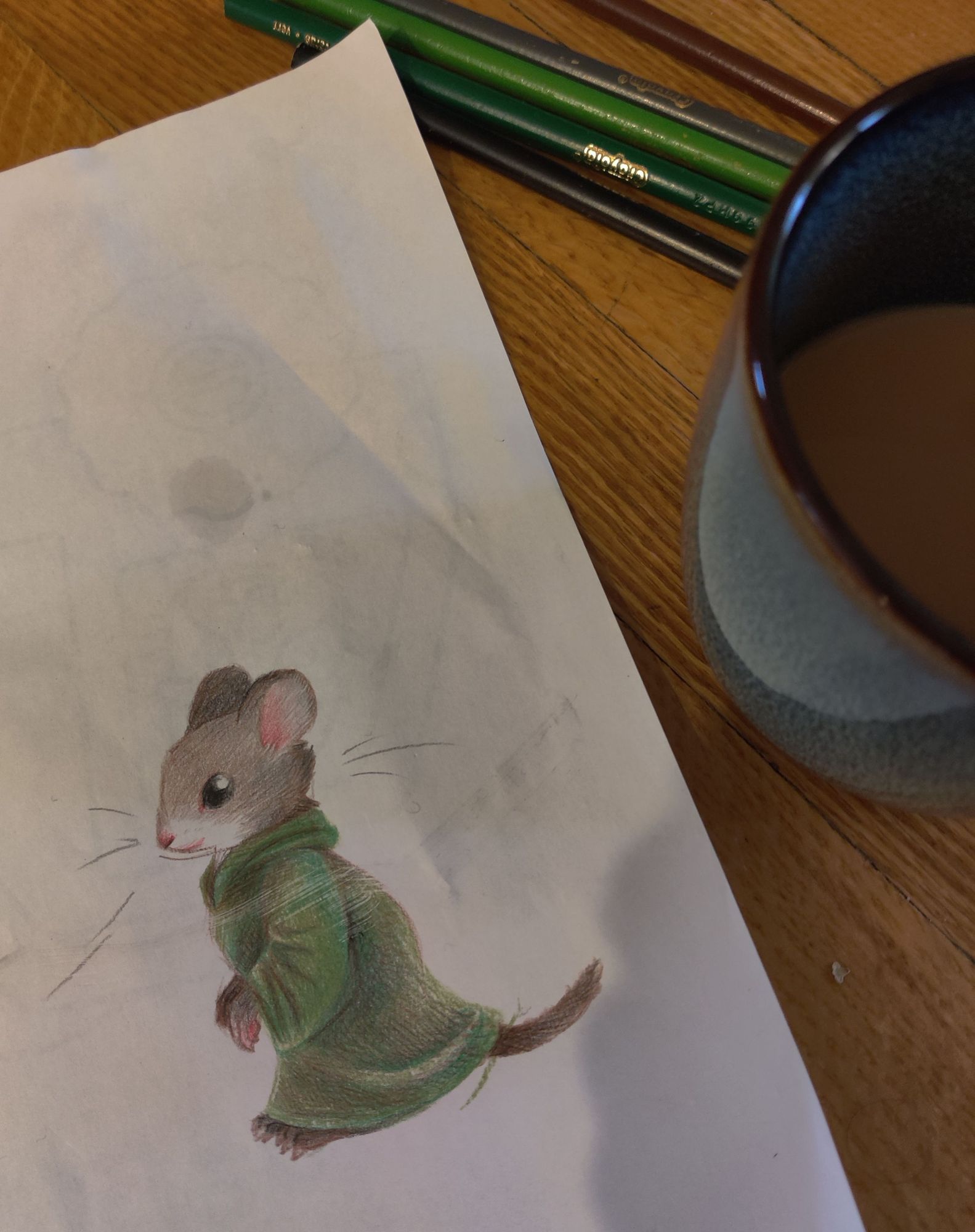 Lightly rendered pencil crayon drawing on a crumpled paper of a Redwall mouse in a green habit. A cup of tea and a handful of pencil crayons are visible on the right.