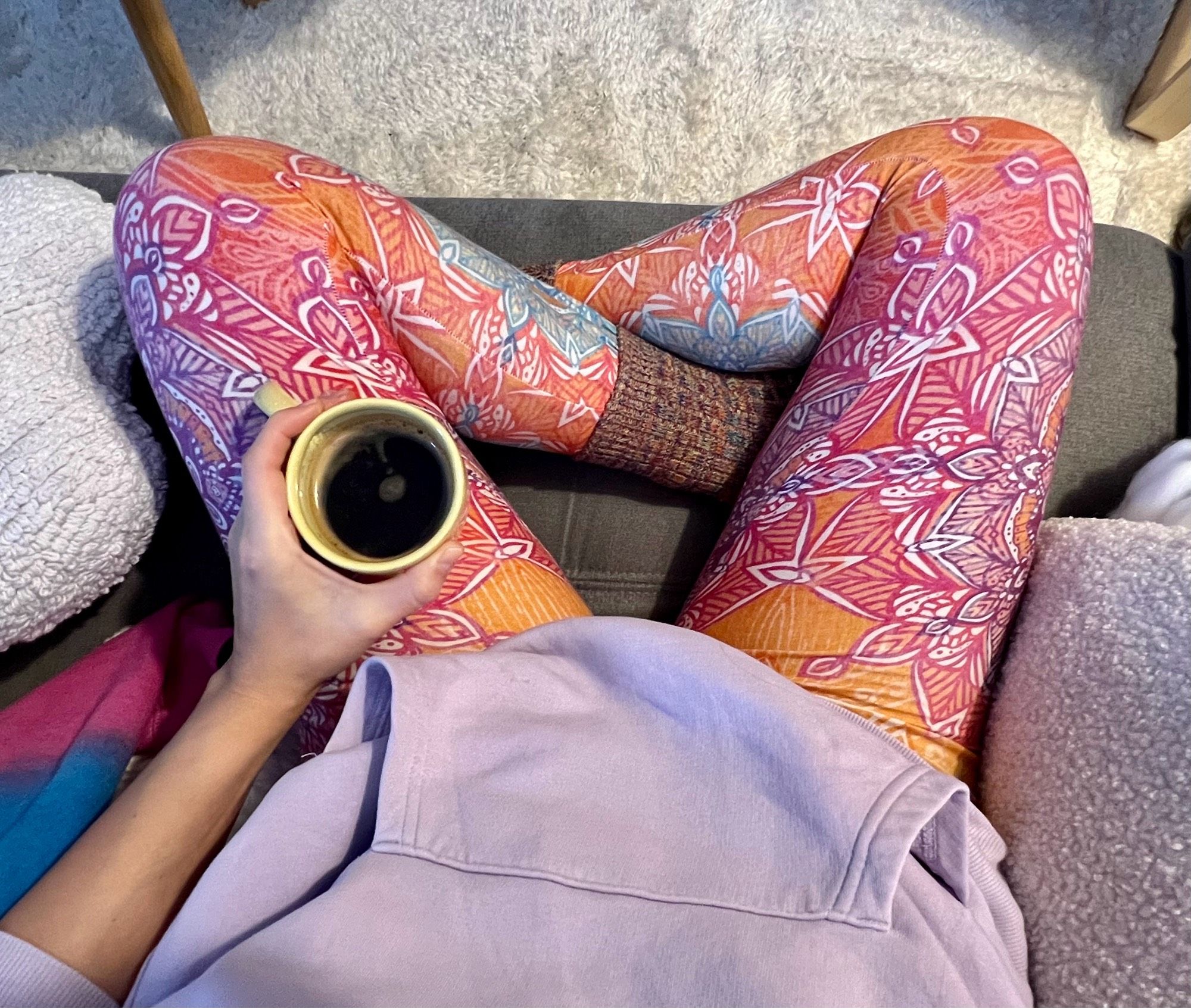 POV-Foto von mir in Yogaleggings und Hoodie, in der linken Hand eine Tasse Kaffee