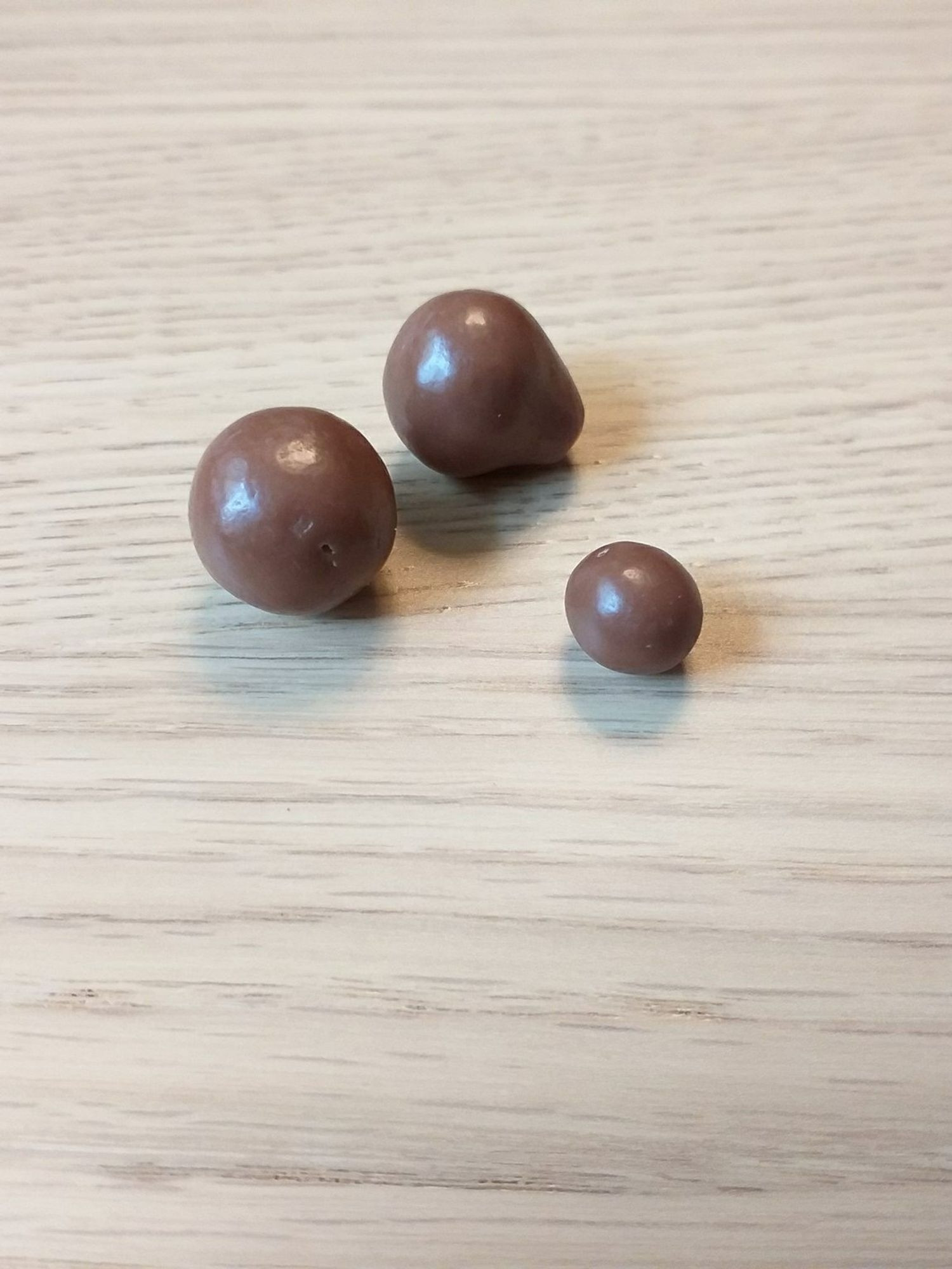 3 bonbons Maltesers, dont 1 tout petit et 1 qui semble avoir un ventre de femme enceinte