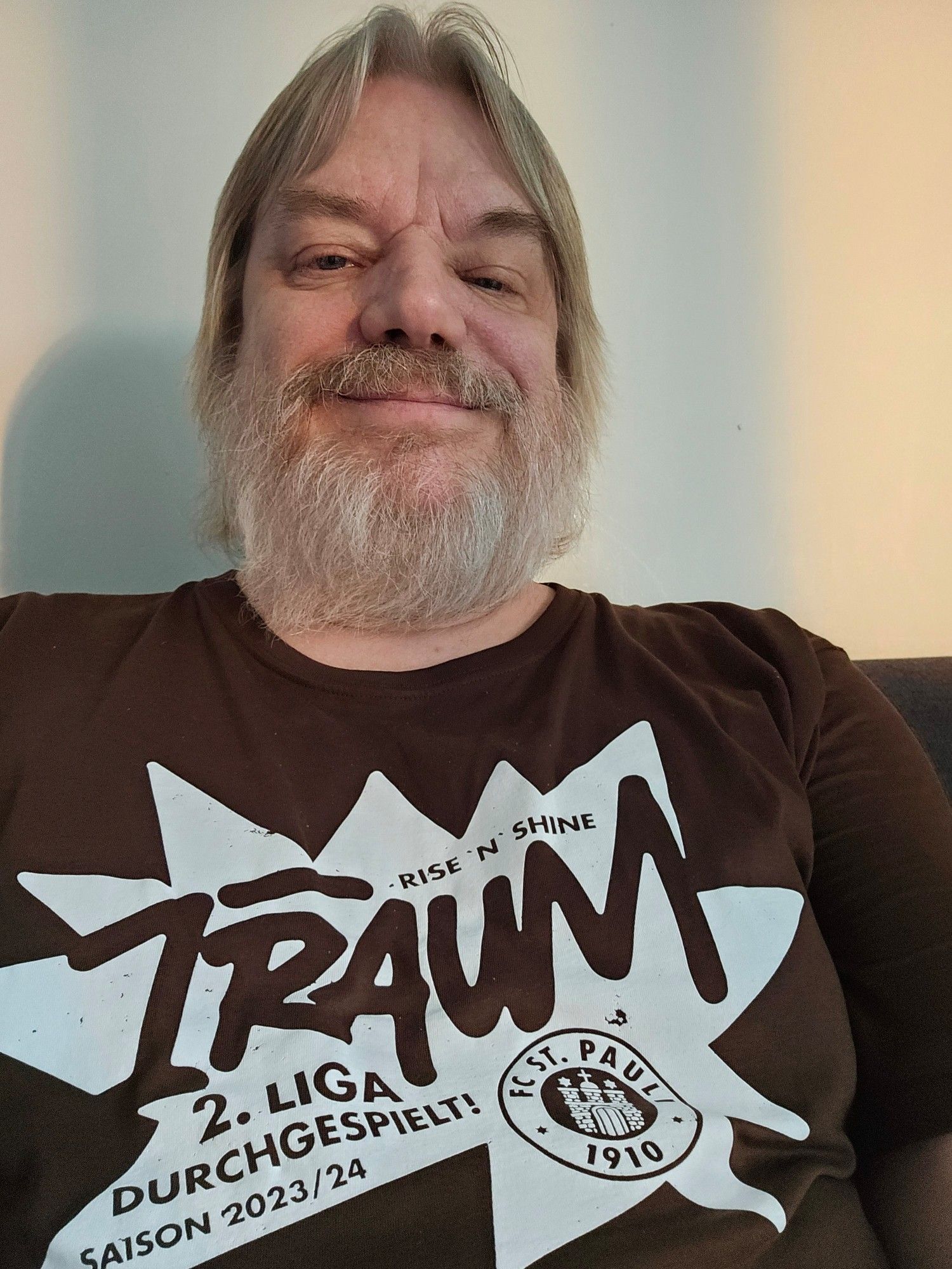 Mann mit Bart und Fan-T-Shirt vom FC St.Pauli aus der Saison 2023/24 mit dem Text 1 Traum, 2.Liga durchgespielt