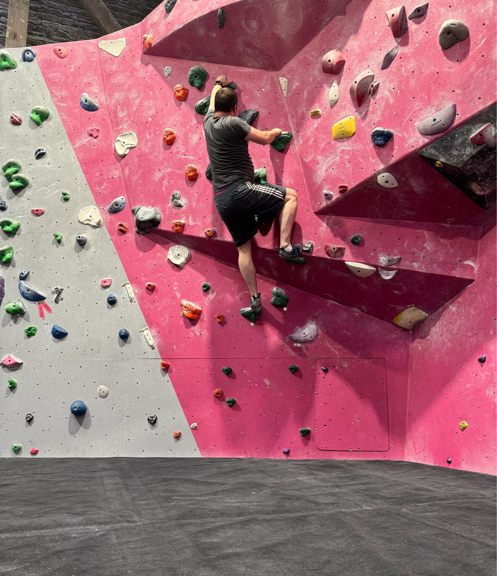 A photograph of me on an indoor climbing wall - halfway up the wall