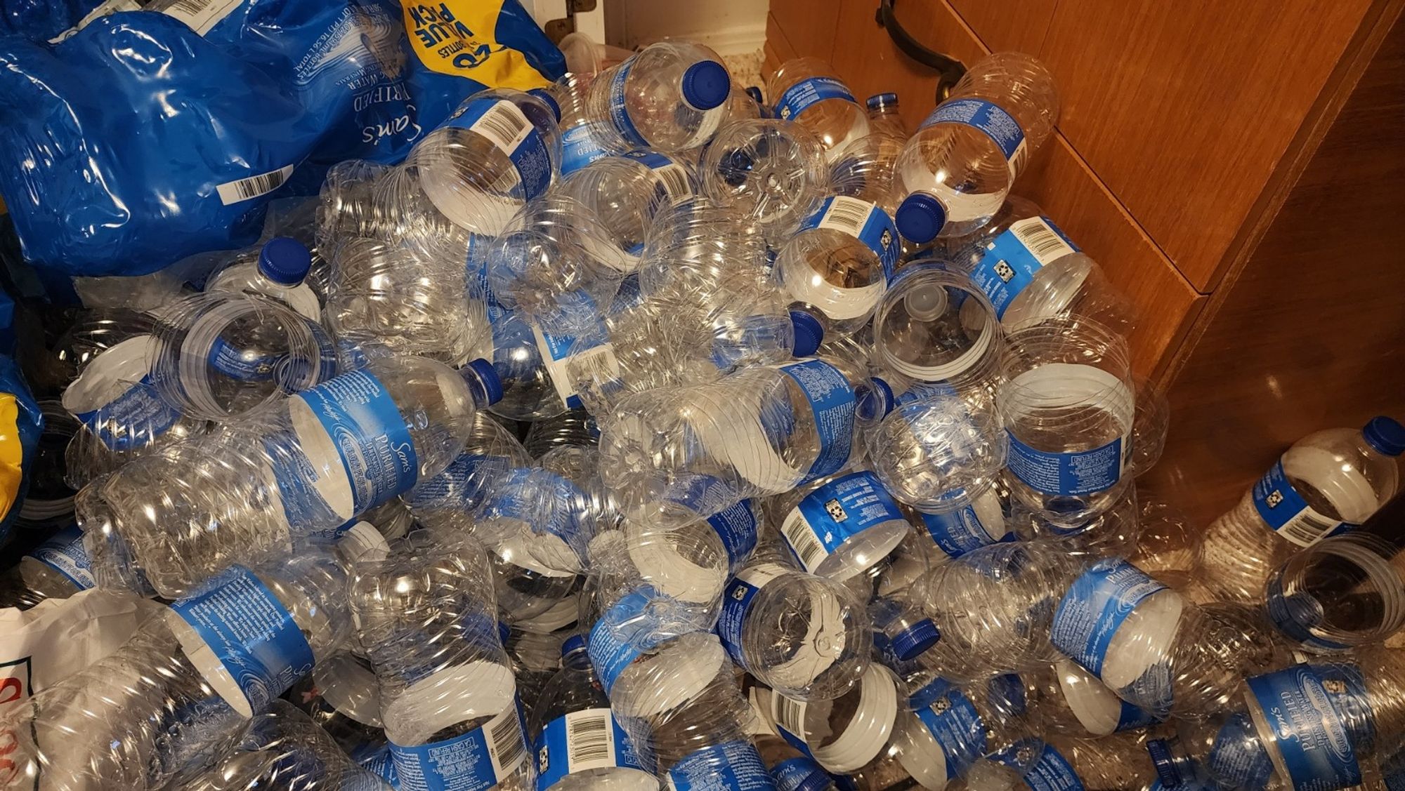 probably 100 empty water bottles stacked in a glorious and shameful pile