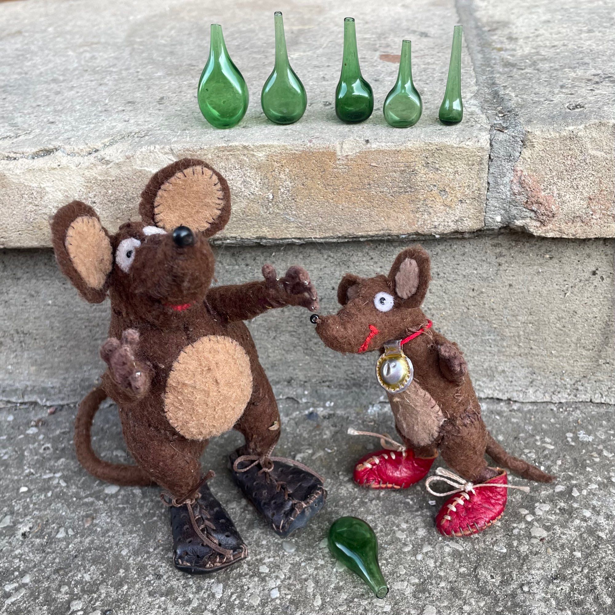 Photo of Minimus and Silvius, the Latin mice, singing about green bottles on a wall (or on the front doorstep!). There are five tiny glass bottles lined up and one on the ground by their feet. Where could the other four bottles have gone?