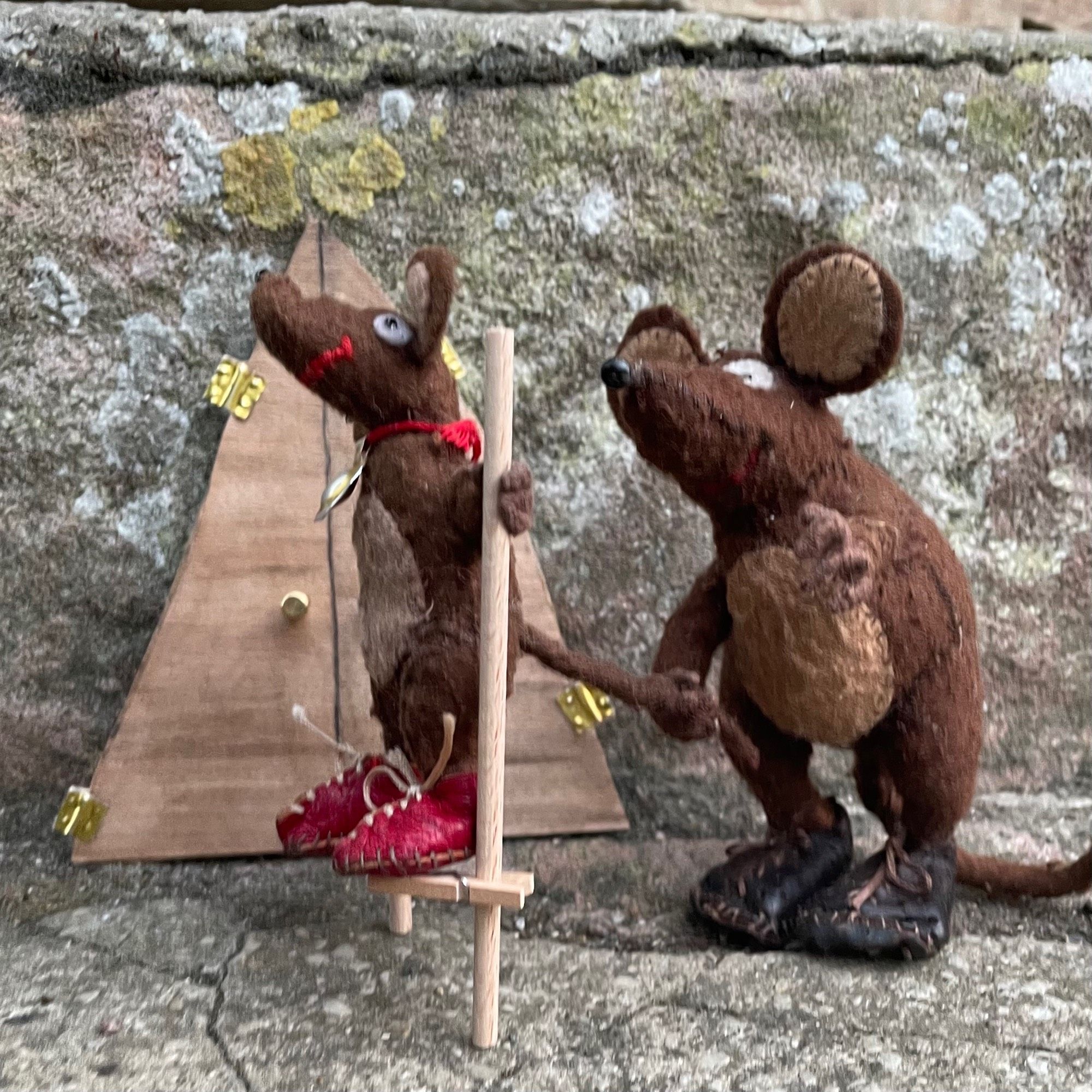 Photo of Minimus and Silvius, the  Latin mice, by the front door of the mousehole. Silvius is trying to walk on home-made stilts, and Minimus his holding his tail to keep him from overbalancing. Stilt-walking is difficult!