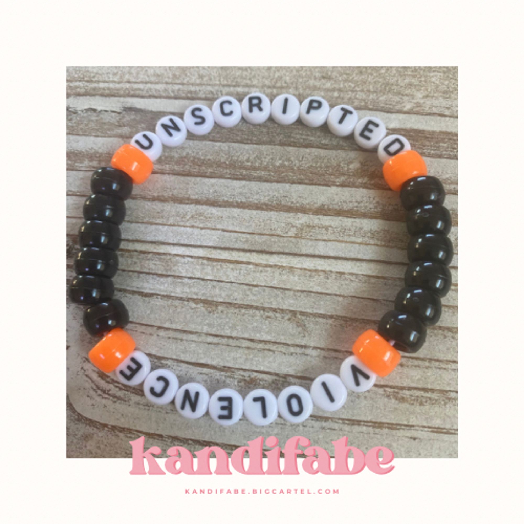 A kandi bracelet that reads “UNSCRIPTED” and “VIOLENCE” in black letters on white circle beads. The phrase is split so one violence is on one side, unscripted on the other side. There are a series of opaque black and orange pony beads between the words.