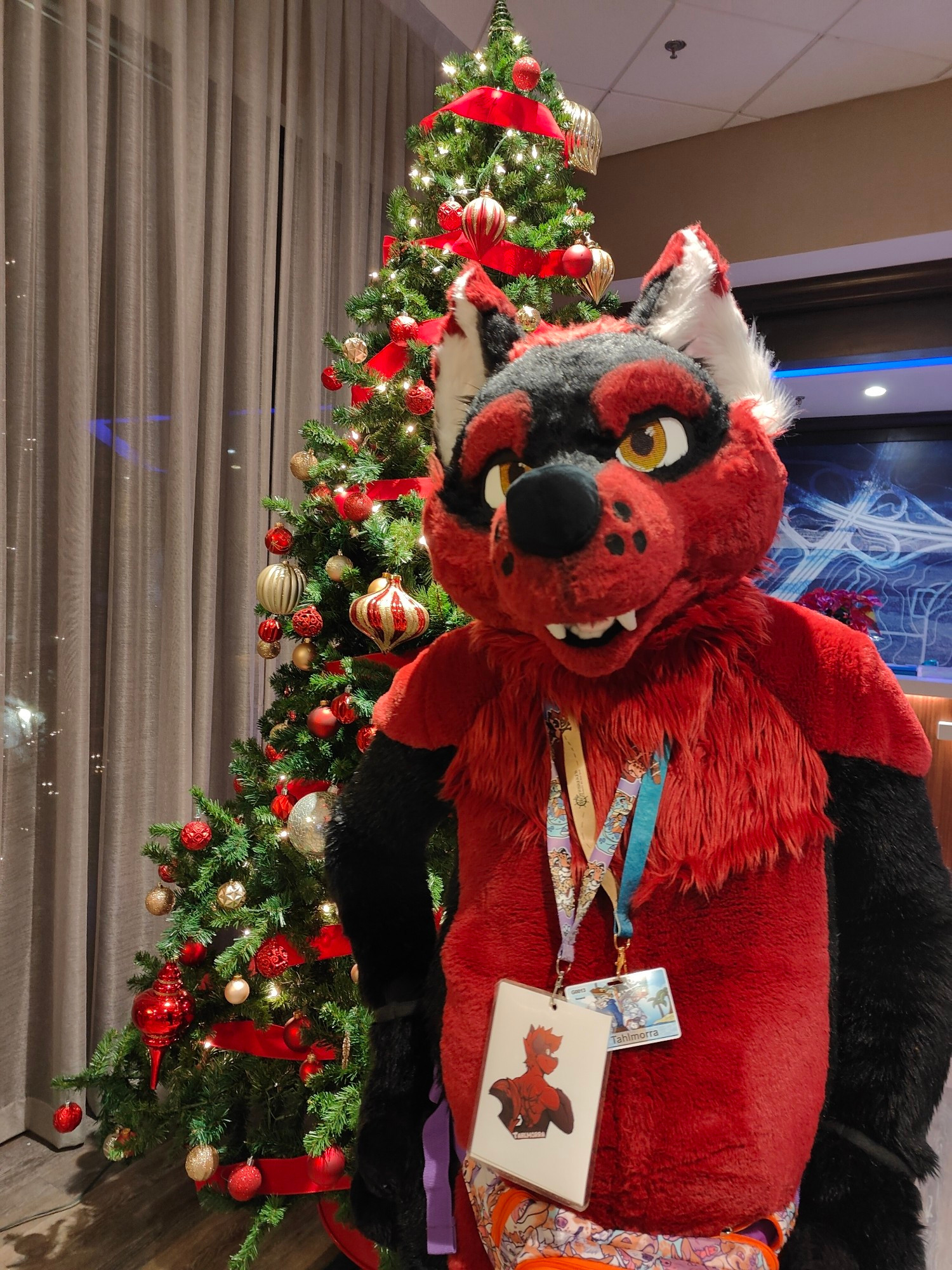 Tahlmorra posing for a photo in the lobby at Bewhiskered. A decorative fir tree stands in the background.