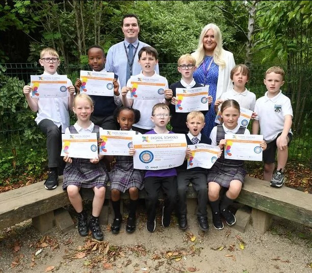 Mrs Calvert HT and Digital Lead Mr O'Neill with children at Glenboig Primary School holding their Digital Schools Awards certificates for achieving the Equitable Creative Coding Award.