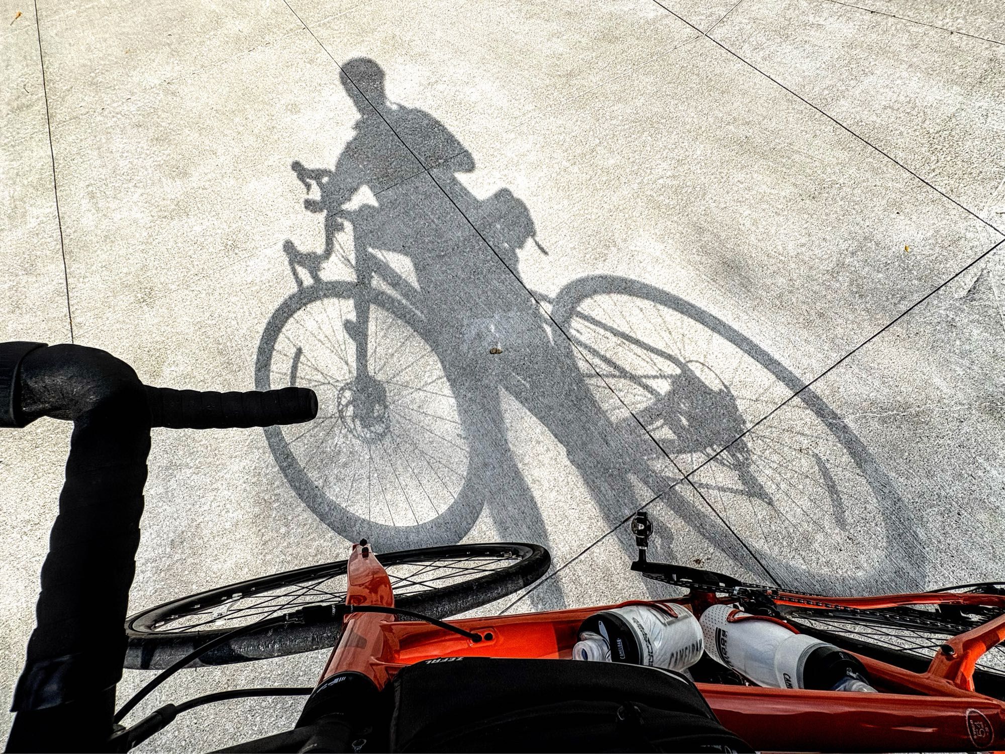 A shadowy self portrait of a cyclist on an orange bicycle.