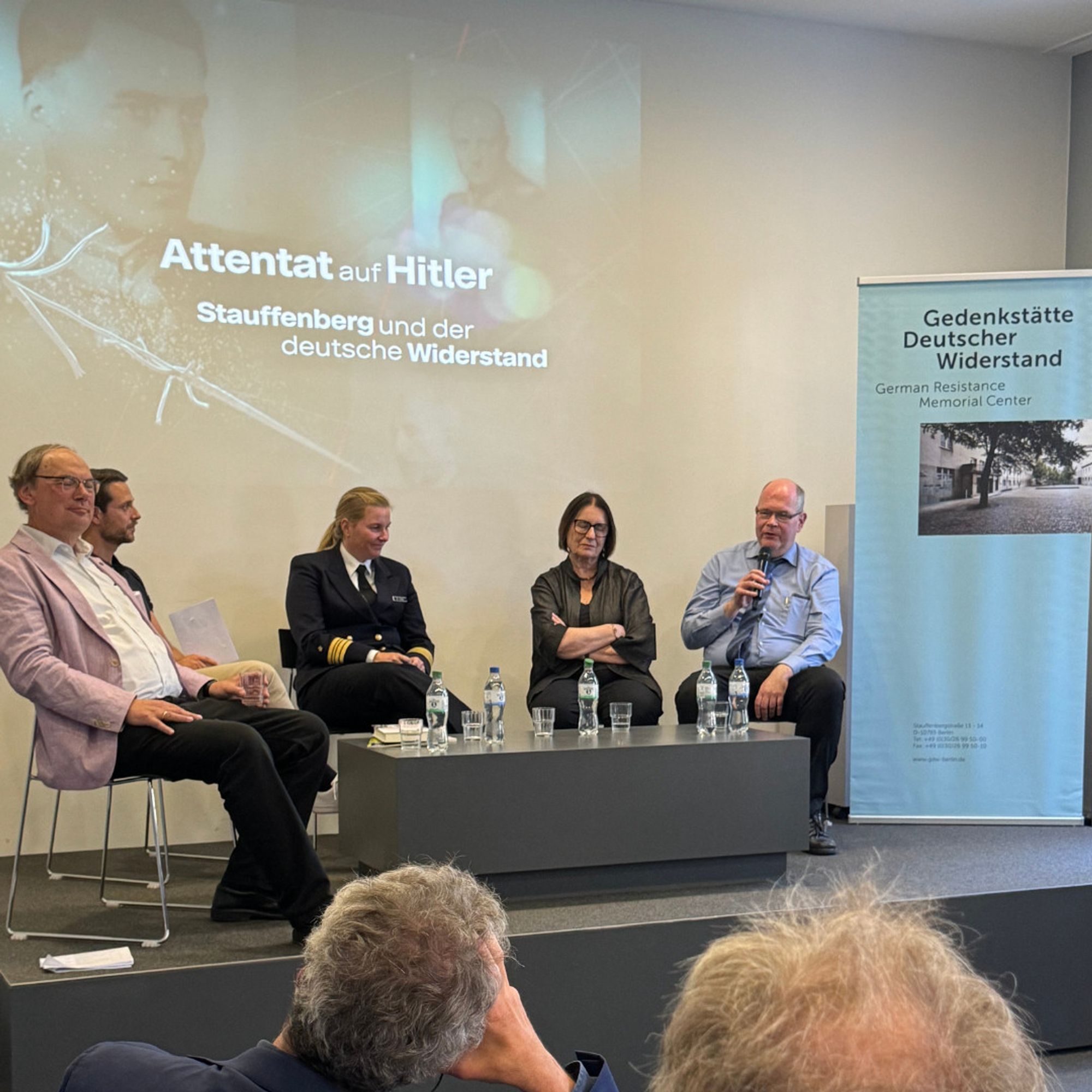 Blick auf das Podium während des Abschlussgesprächs nach der Filmvorführung. Von links nach rechts: Niko Lamprecht, Bundesvorsitzender des Verbands der Geschichtslehrerinnen und - lehrer Deutschlands (VGD), Mirko Drotschman, ZDF-Presenter, Fregattenkapitän Dr. Leonie Hieck, Referentin für Erinnerungskultur beim Bundesministerium der Verteidigung, Irina Scherbakowa, russische Dissidentin und Mitbegründerin der Organisation Memorial, Prof. Dr. Johannes Tuchel, Leiter der Gedenkstätte Deutscher Widerstand. Auf der Wand ist das Backgroundbild des Films mit dem Filmtitel zu sehen. Rechts vom Podium steht ein Roll-up-Banner der Gedenkstätte Deutscher Widerstand.
© Gedenkstätte Deutscher Widerstand