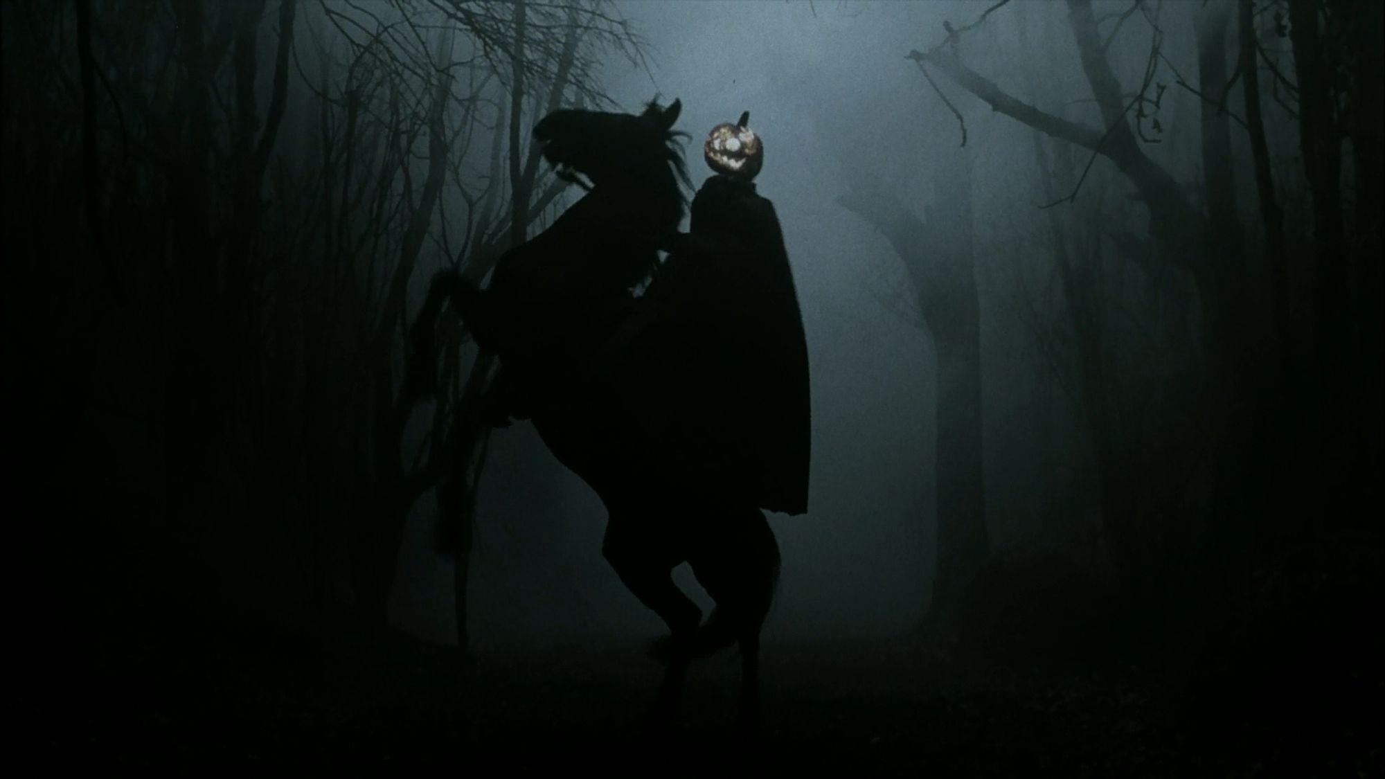 Sleepy Hollow (1999). In a dark and foggy forest, The Headless Horseman holding a flaming jack-o-lantern aloft as his horse rears up on its hind legs.