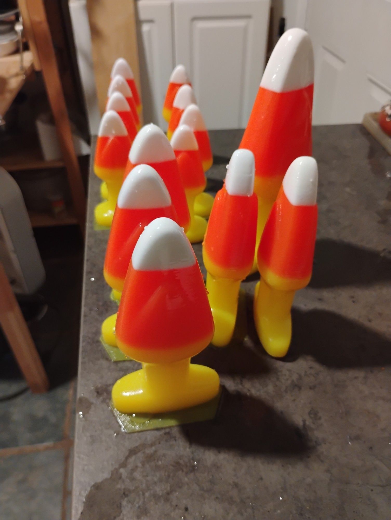 a bunch of freshly popped untrimmed candy corn buttplugs on the corner of a counter, in three sizes.