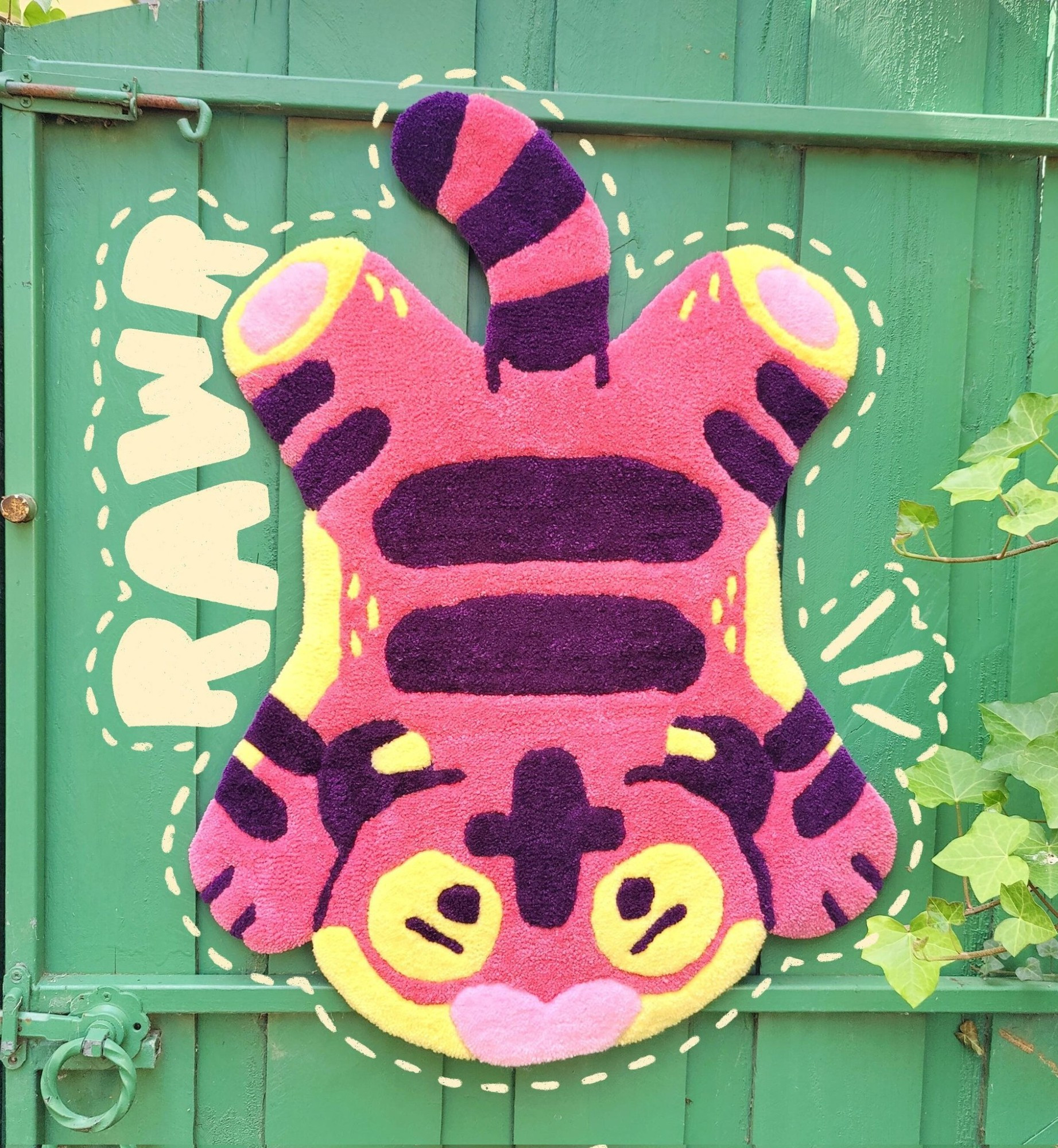 A handmade pink tiger rug, displayed on a green fence door backdrop.