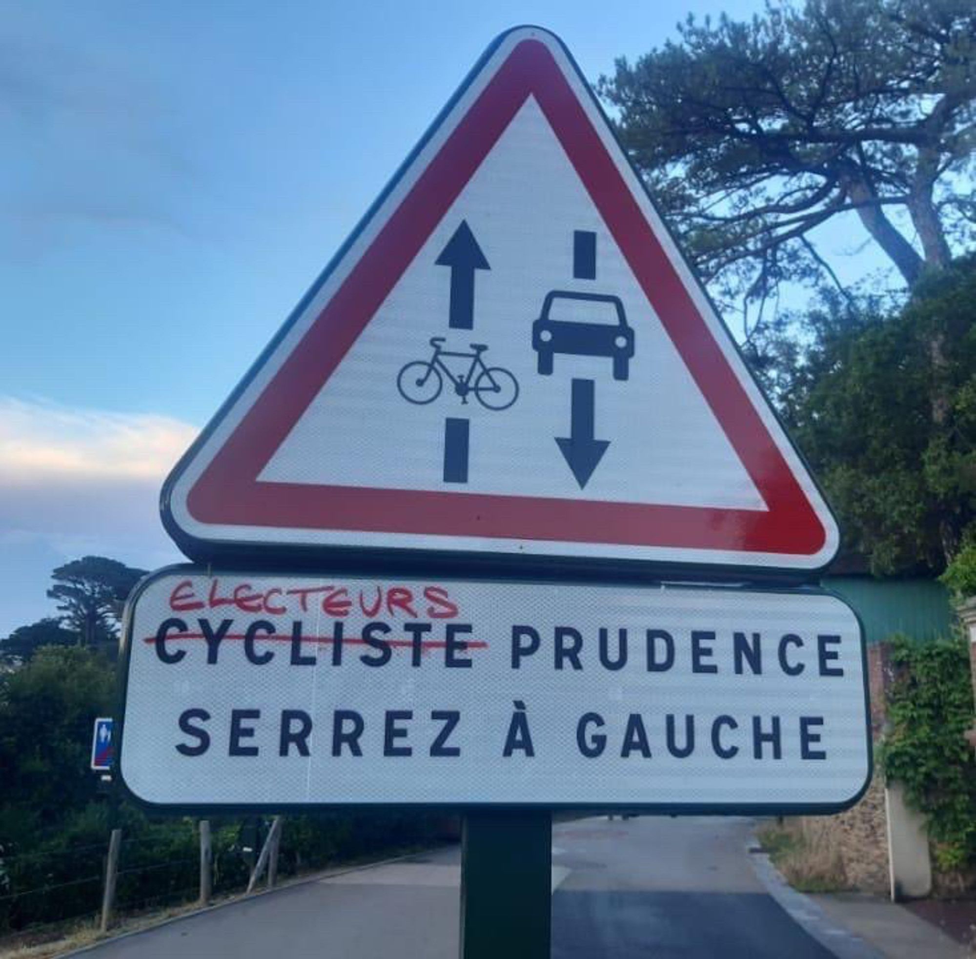 Panneau "cycliste, prudence ! Serrez à gauche" où le mot "cycliste" a été barré et remplacé par "électeurs"