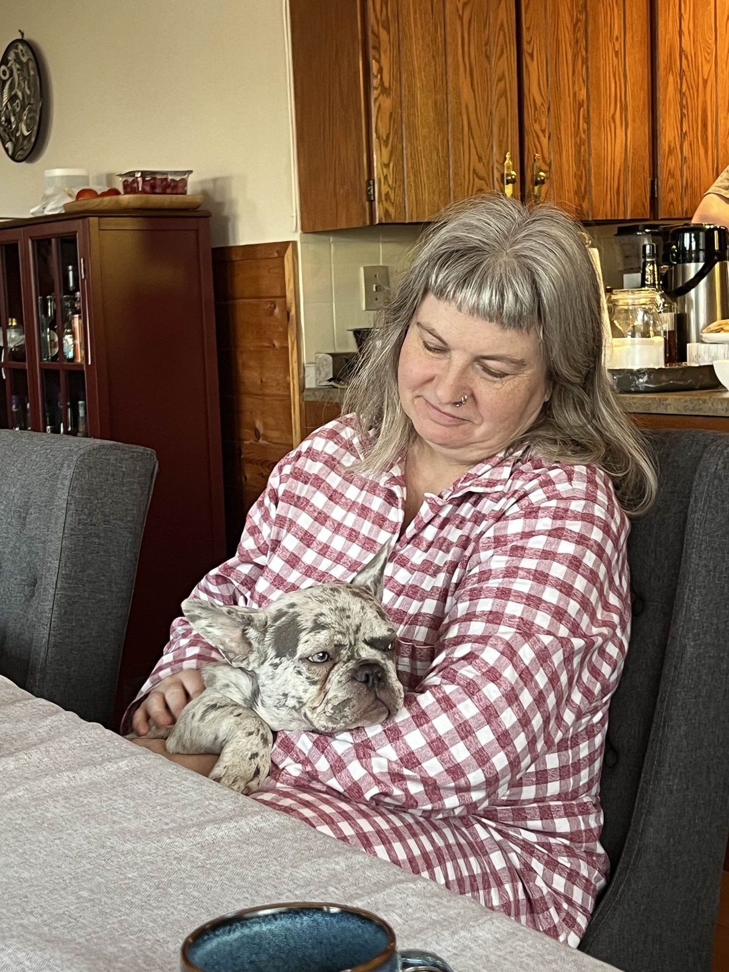 A pic of Rilla in flannel pyjamas holding a small wrinkly grey dog with googly eyes.