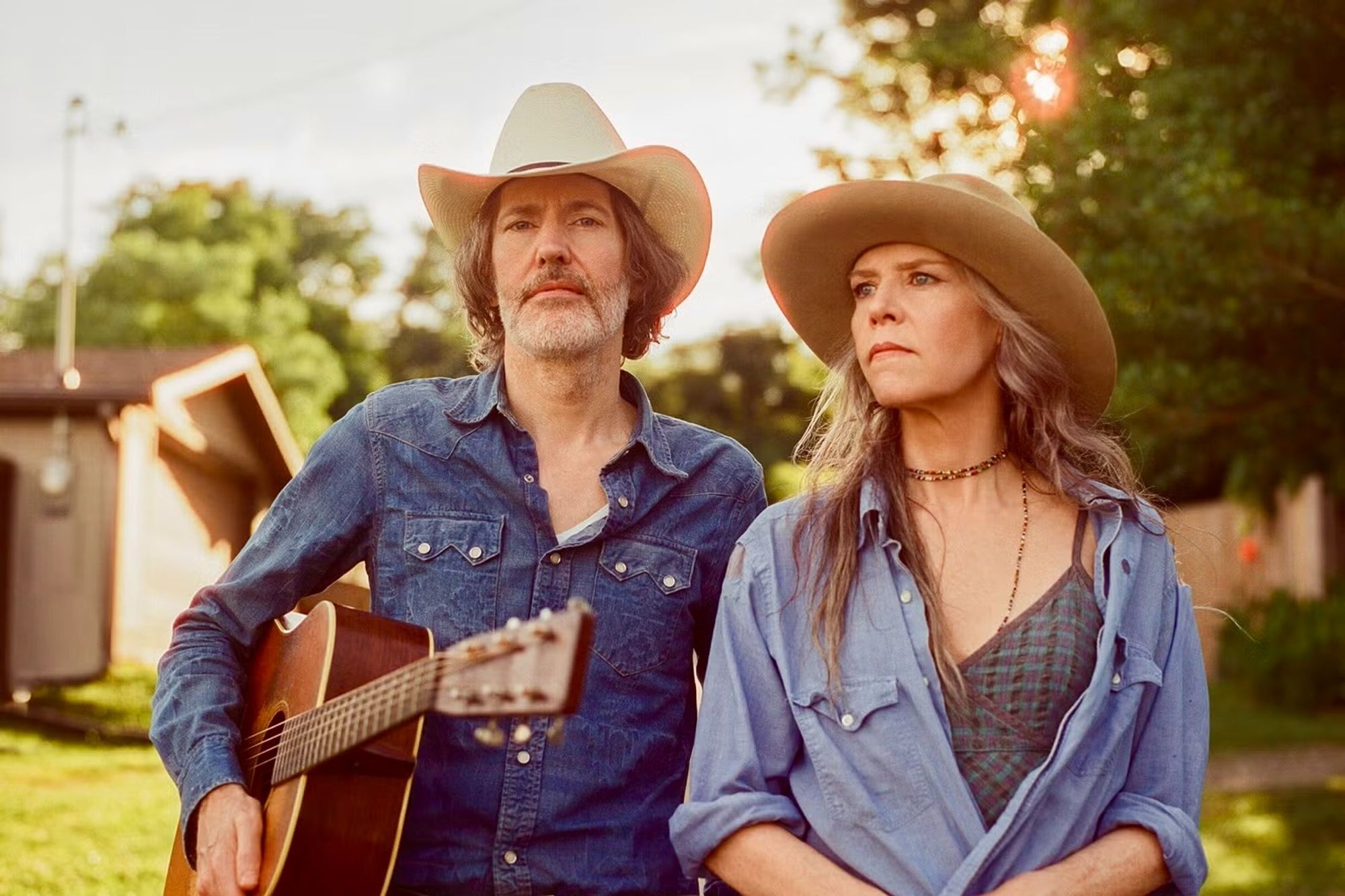 David Rawlings with a guitar and Gillian Welch, both in cowboy hats.