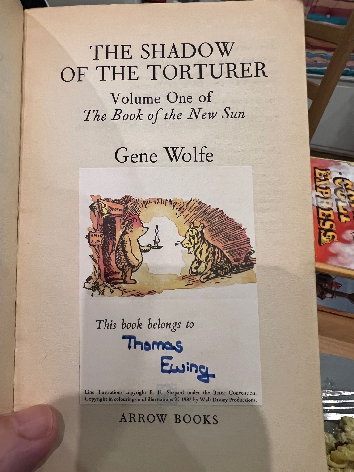 The title page of the Arrow edition of The Shadow Of The Torturer by Gene Wolfe - attached to it is a  bookplate showing Pooh and Tigger with “This book belongs to Thomas Ewing” underneath