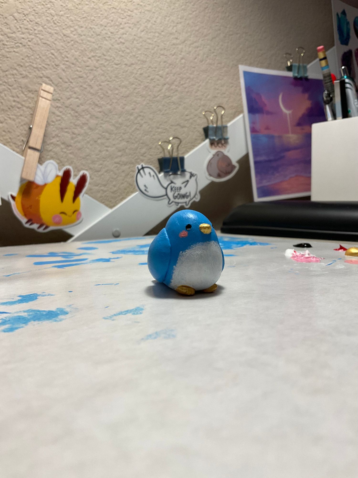 A freshly painted little blue and white bird made of sculpey.