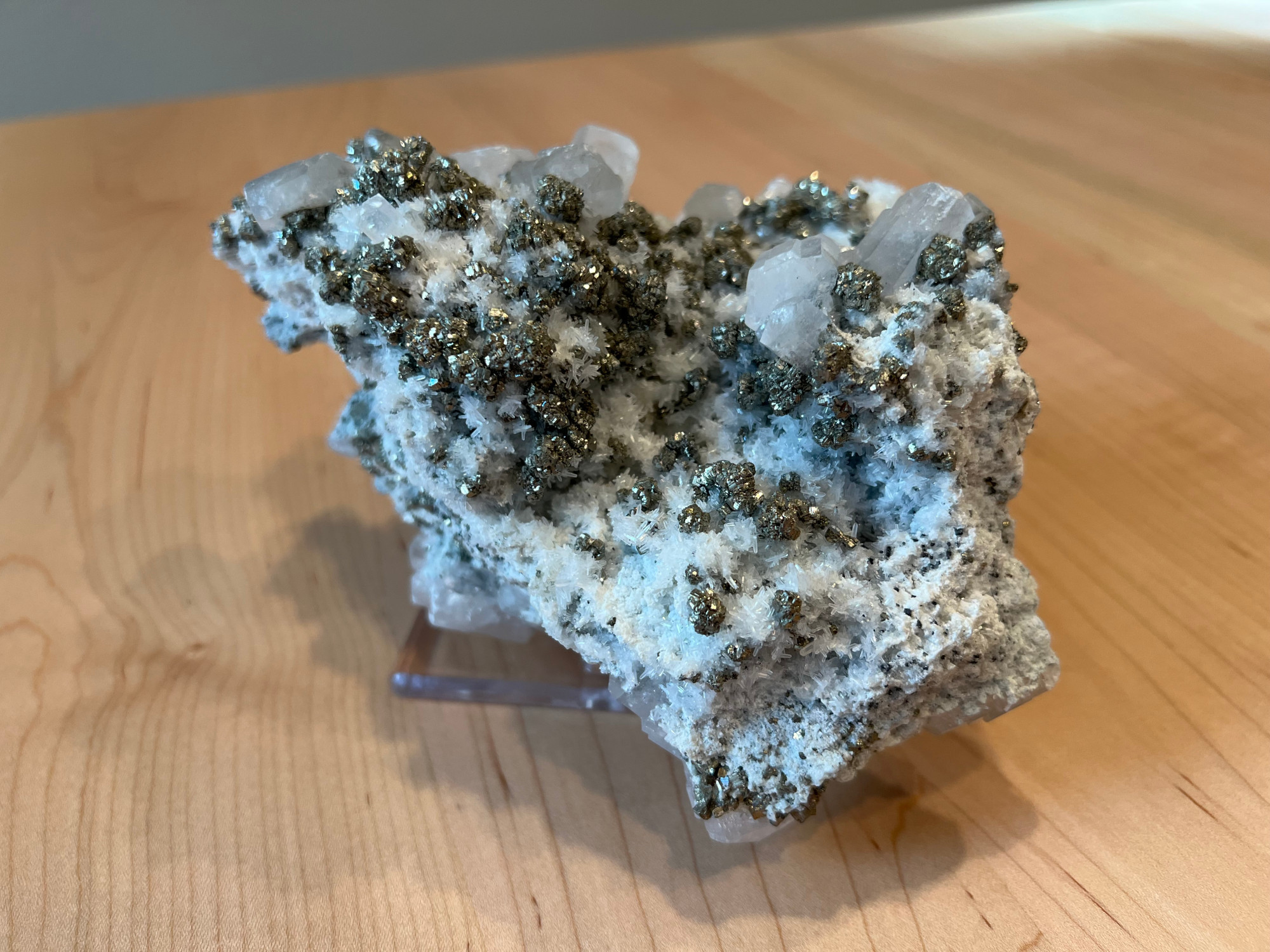 A huge mineral specimen dotted with chalcopyrite, pyrite, and sphalerite in addition to white calcite and quartz crystals.