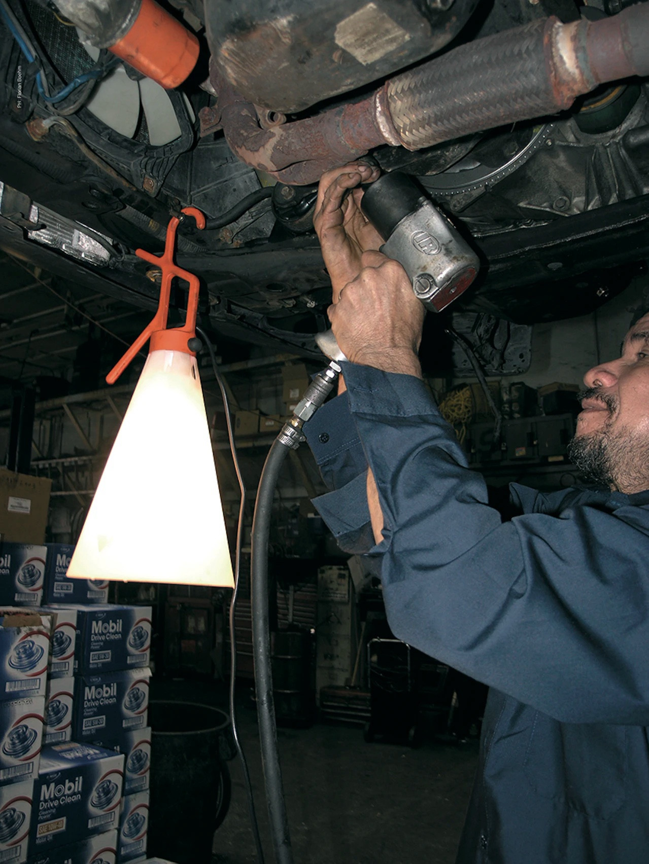 Auch die Flos Lampe aber in einem arbeitssetting, an einem Rohr aufgehängt während jmd was bohrt