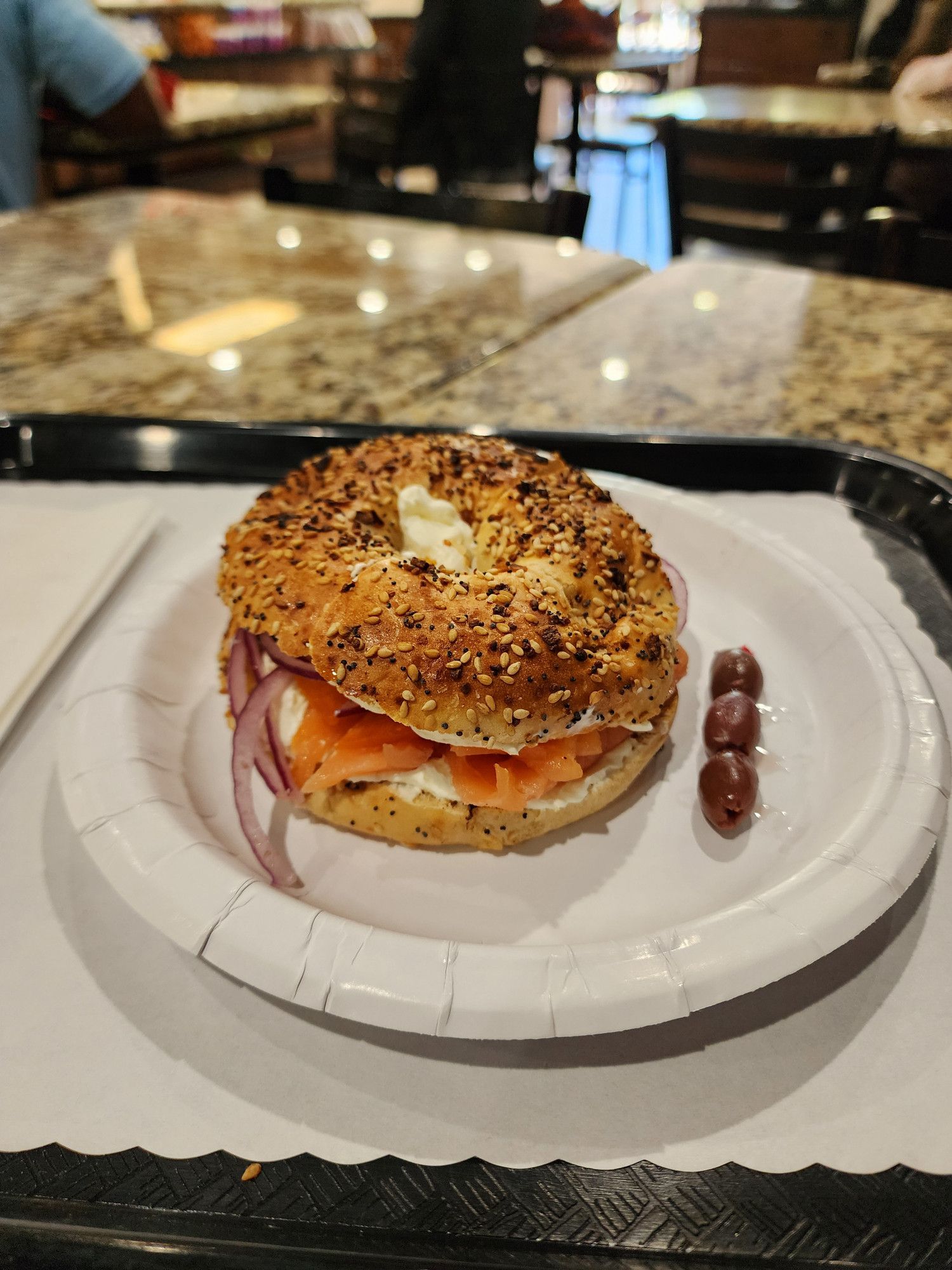 An everything bagel with cream cheese, lox, tomatoes, red onion, capers, and Kalamata olives.