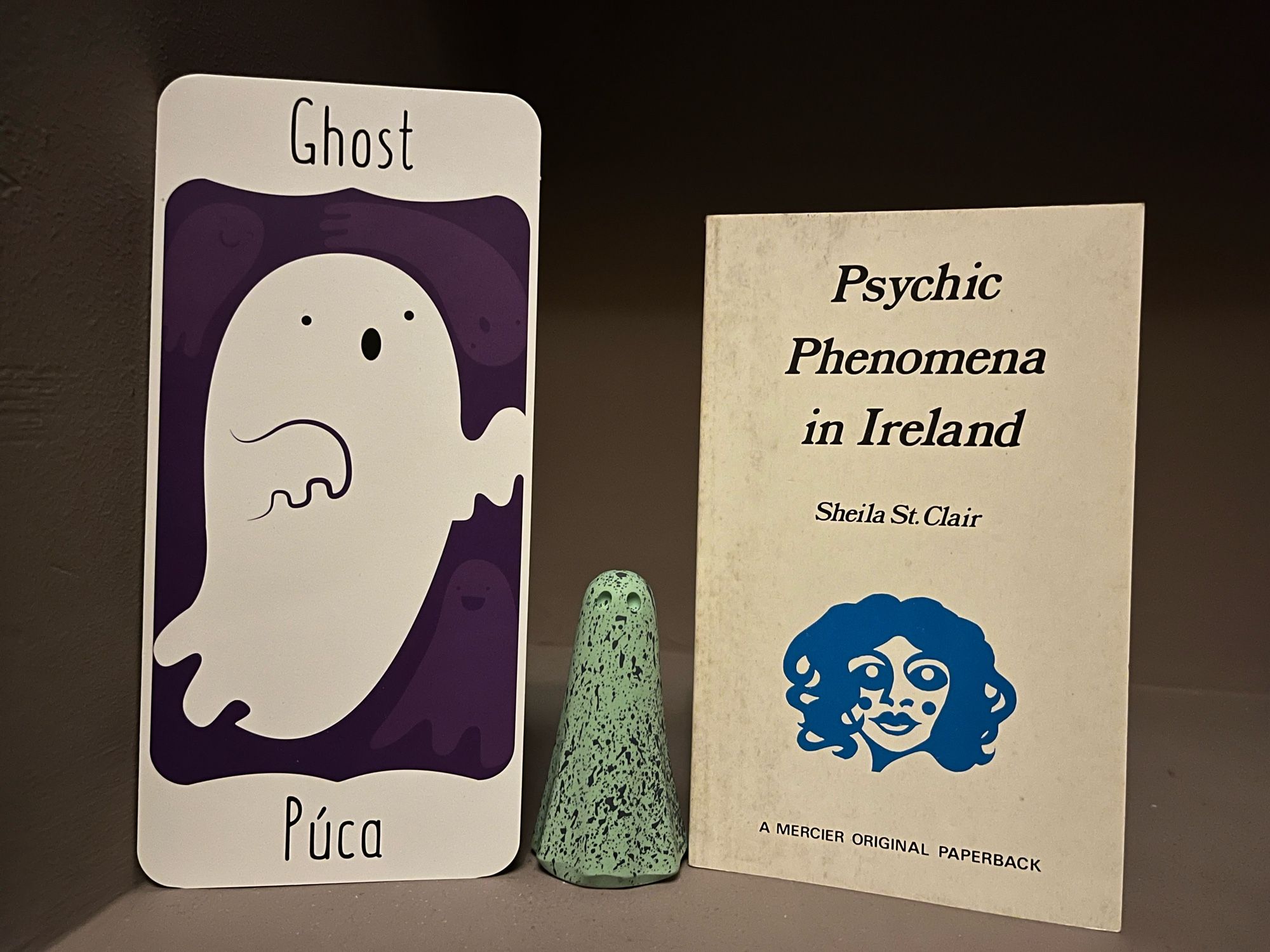 Irish-language flash card with ghost/púca, a York Ghost Merchants ghost and a copy of Psychic Phenomena in Ireland by Sheila St Clair