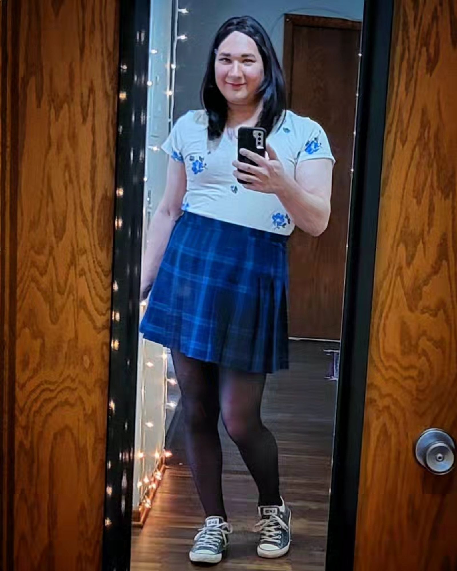 Suzies outfit: Brunette hair, off-white tee shirt with blue flowers, blue and green plaid pleated skirt, black tights, gray low-tops.